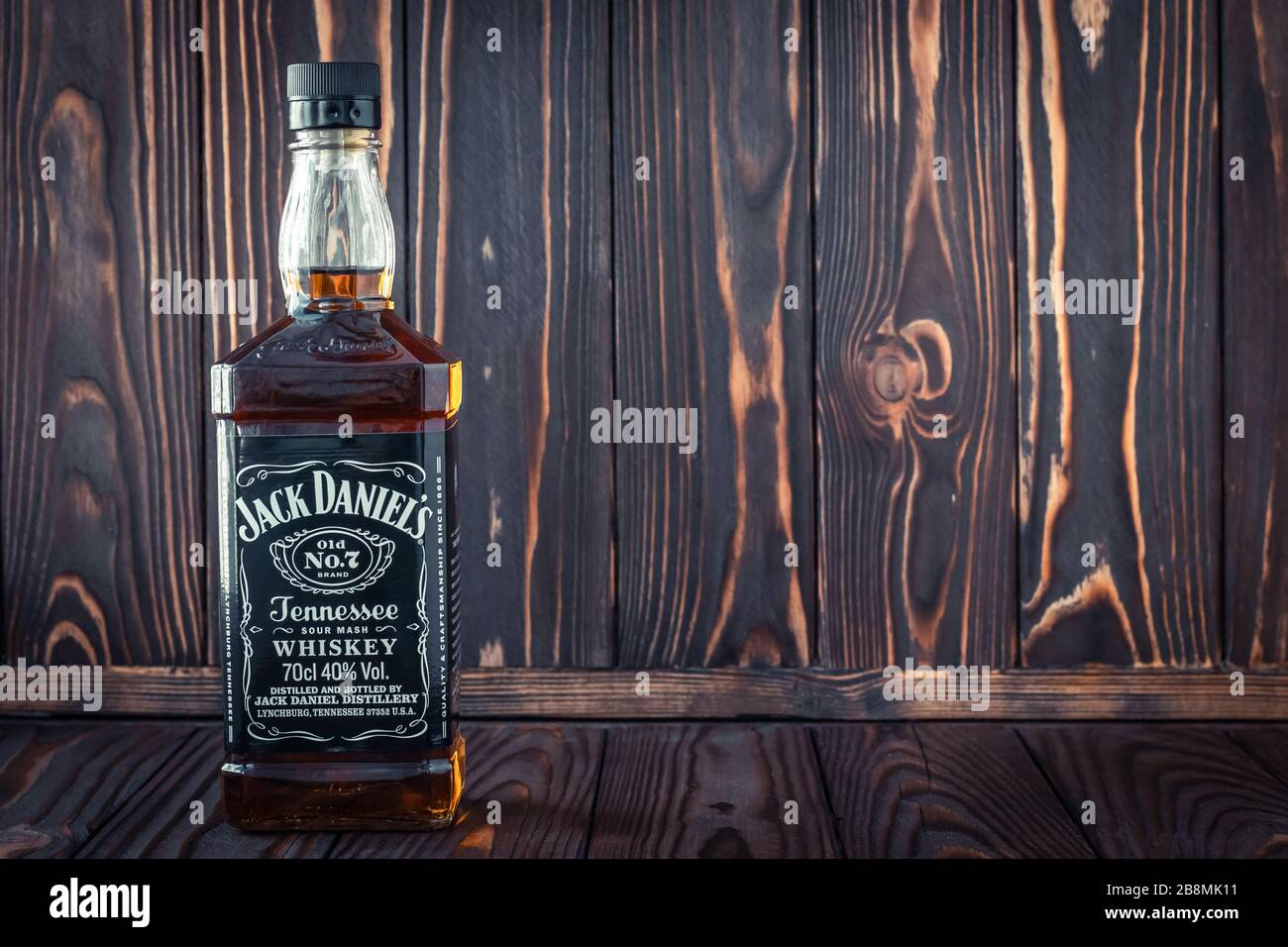 Kharkiv, Ucraina, 22 marzo 2020: Una bottiglia di vetro piena di whisky americano Jack Daniel su sfondo di legno marrone scuro. Bevanda forte originale. Vuoto sp Foto Stock