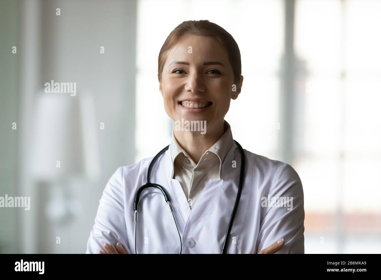 Headshot ritratto medico femmina in cappotto bianco posa in interno Foto Stock