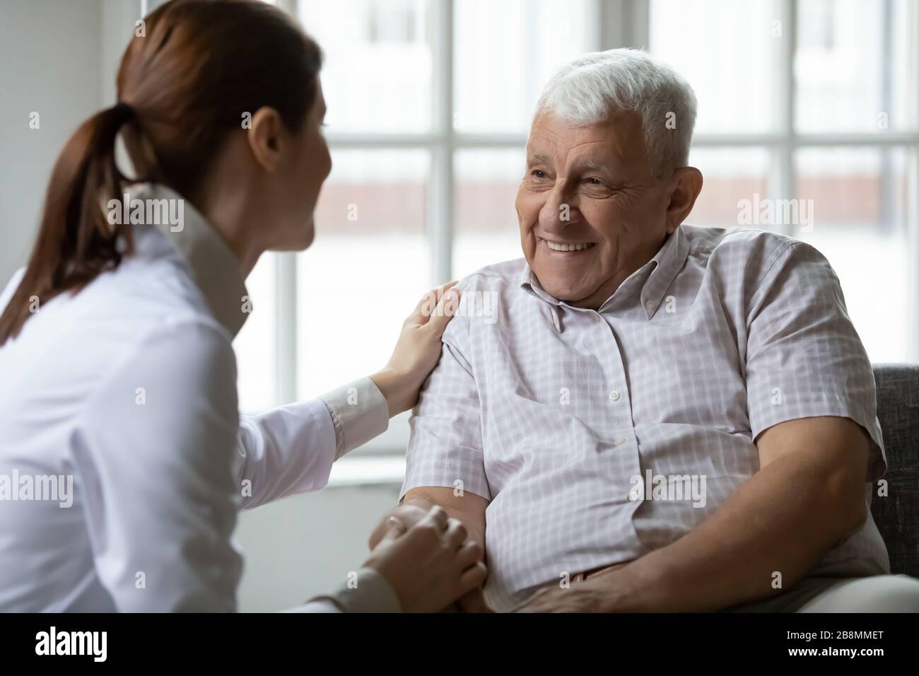 L'infermiere parla al vecchio paziente tiene la mano mostrando gentilezza Foto Stock