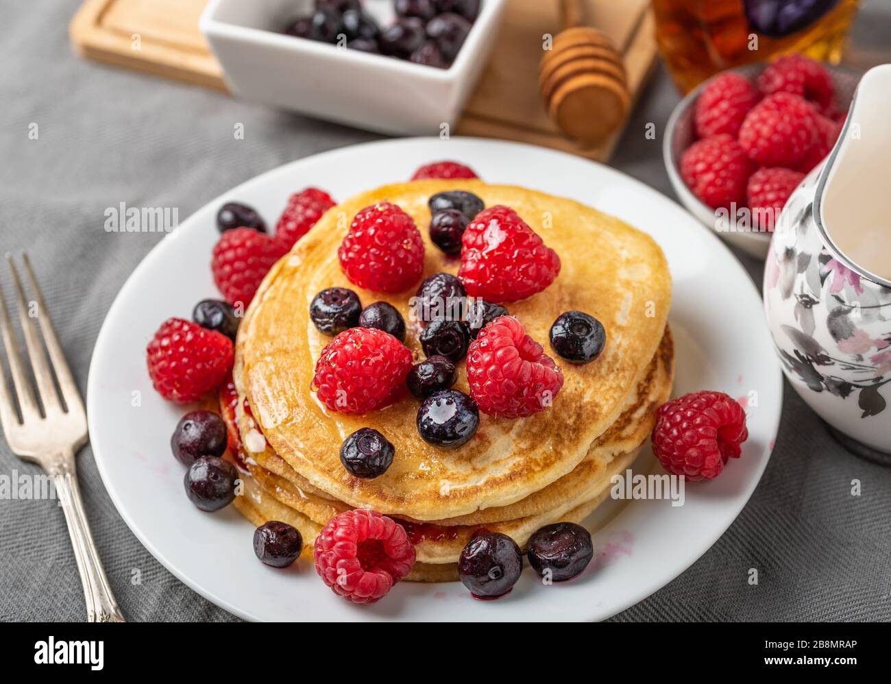 Dolce frittelle fatte in casa con lamponi e mirtilli sulla piastra bianca. Foto Stock