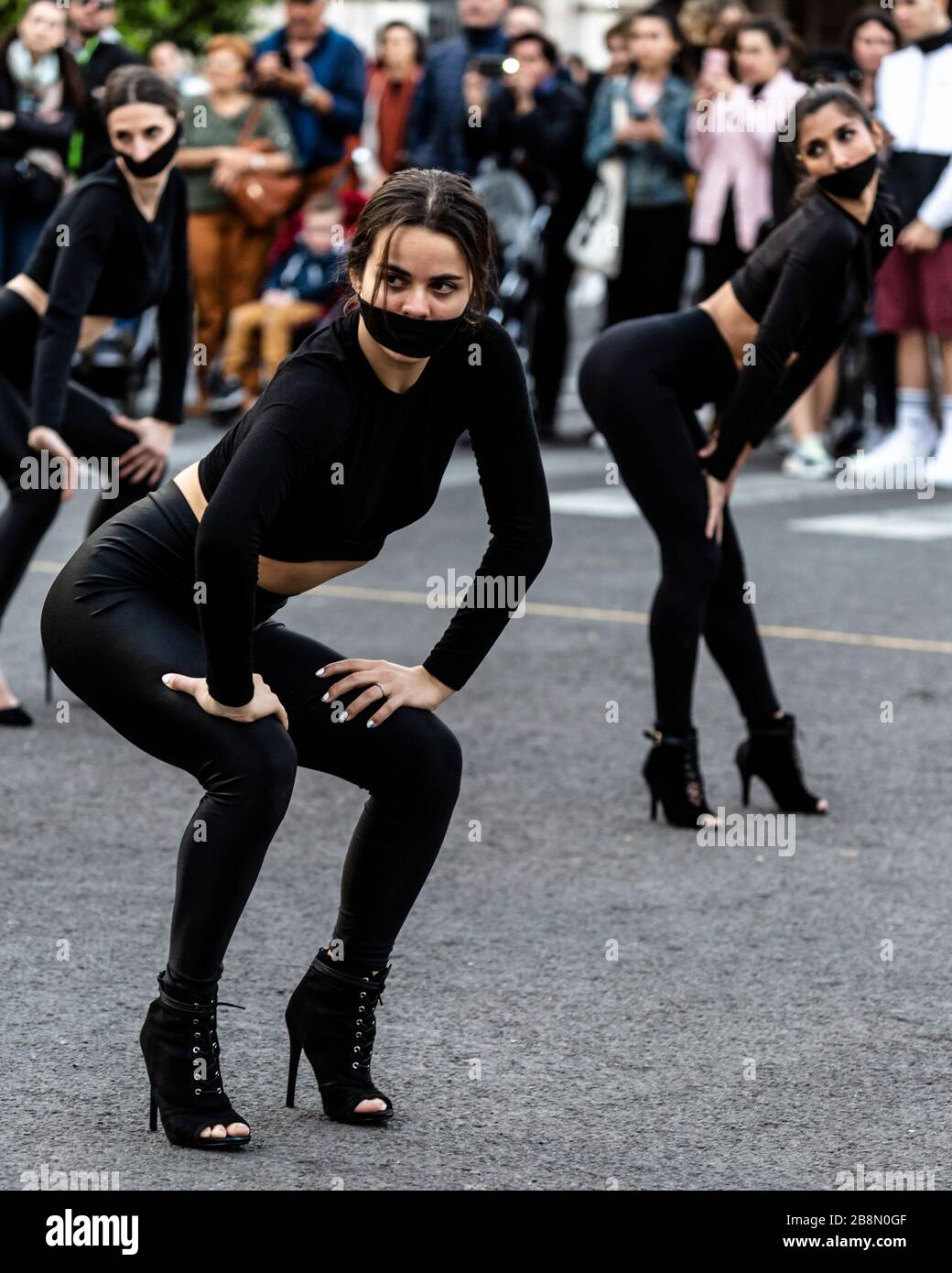 Troupe da ballo vestita con maschere facciali nere sopra la bocca, International Women's Day 2020, Valencia, Spagna. Foto Stock