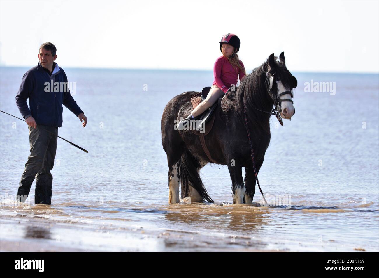 Padre e figlia in un viaggio fuori con il loro pony alla spiaggia di Ainsdale in una giornata di primavera soleggiata Foto Stock