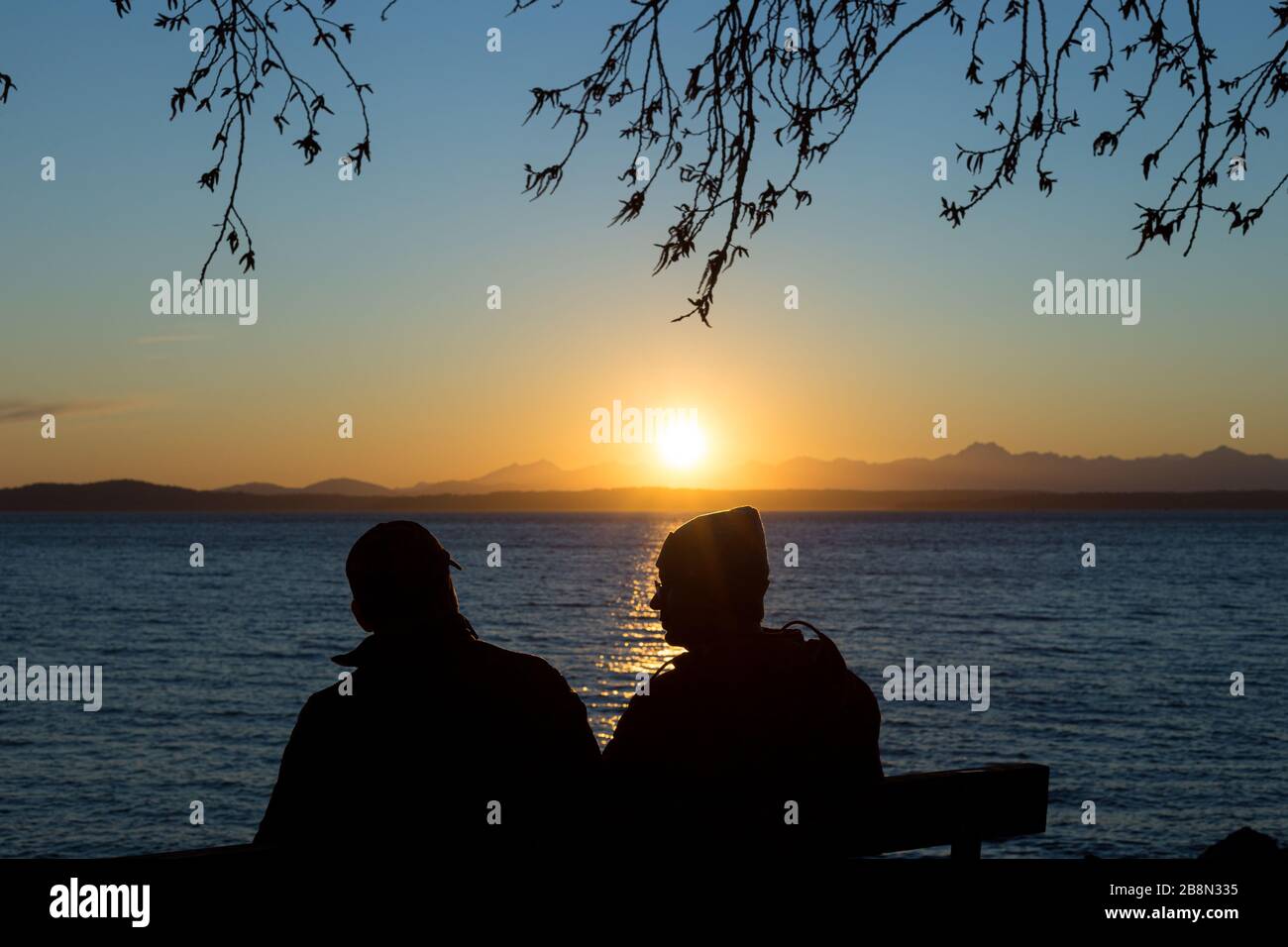 Due persone godono di un bel tramonto su Puget Sound e le Olympic Mountains Foto Stock