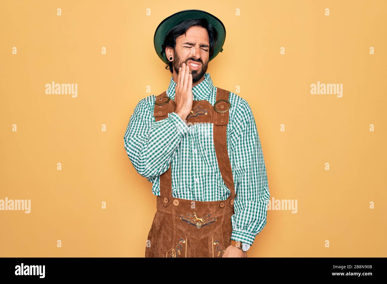 Giovane uomo bello che indossa traditional tedesco octoberfest custome  mangiare salsiccia molto felice indicando con mano e dito Foto stock - Alamy