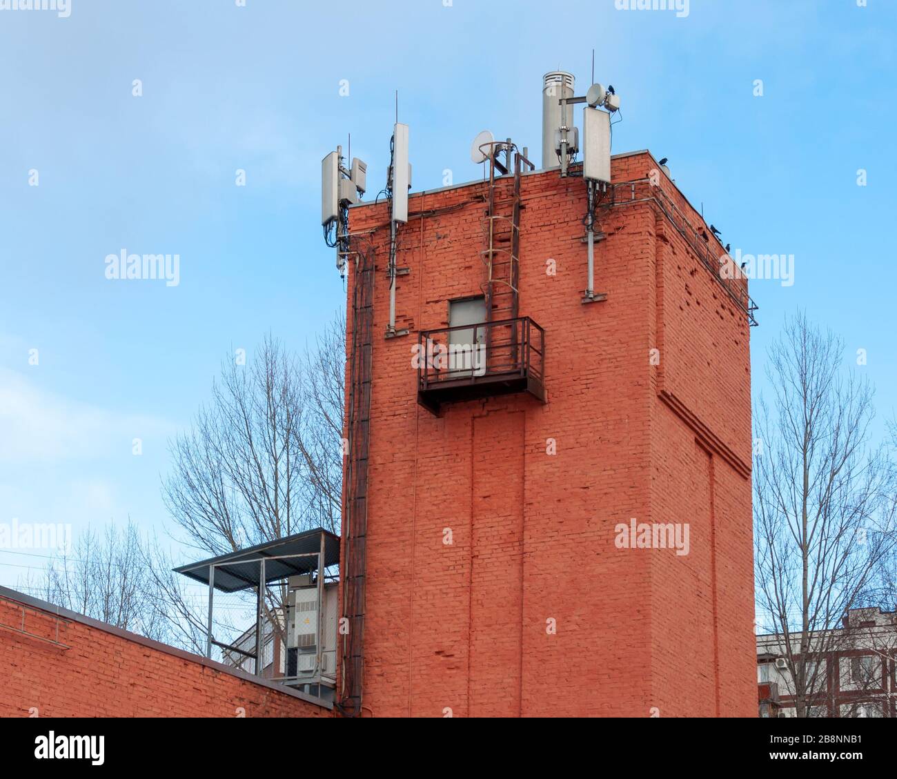 Apparecchiature per la comunicazione cellulare e la trasmissione dati. Antenne 2G, 3G, 4G, 5G installate sul tetto di una vecchia torre d'acqua in mattoni Foto Stock