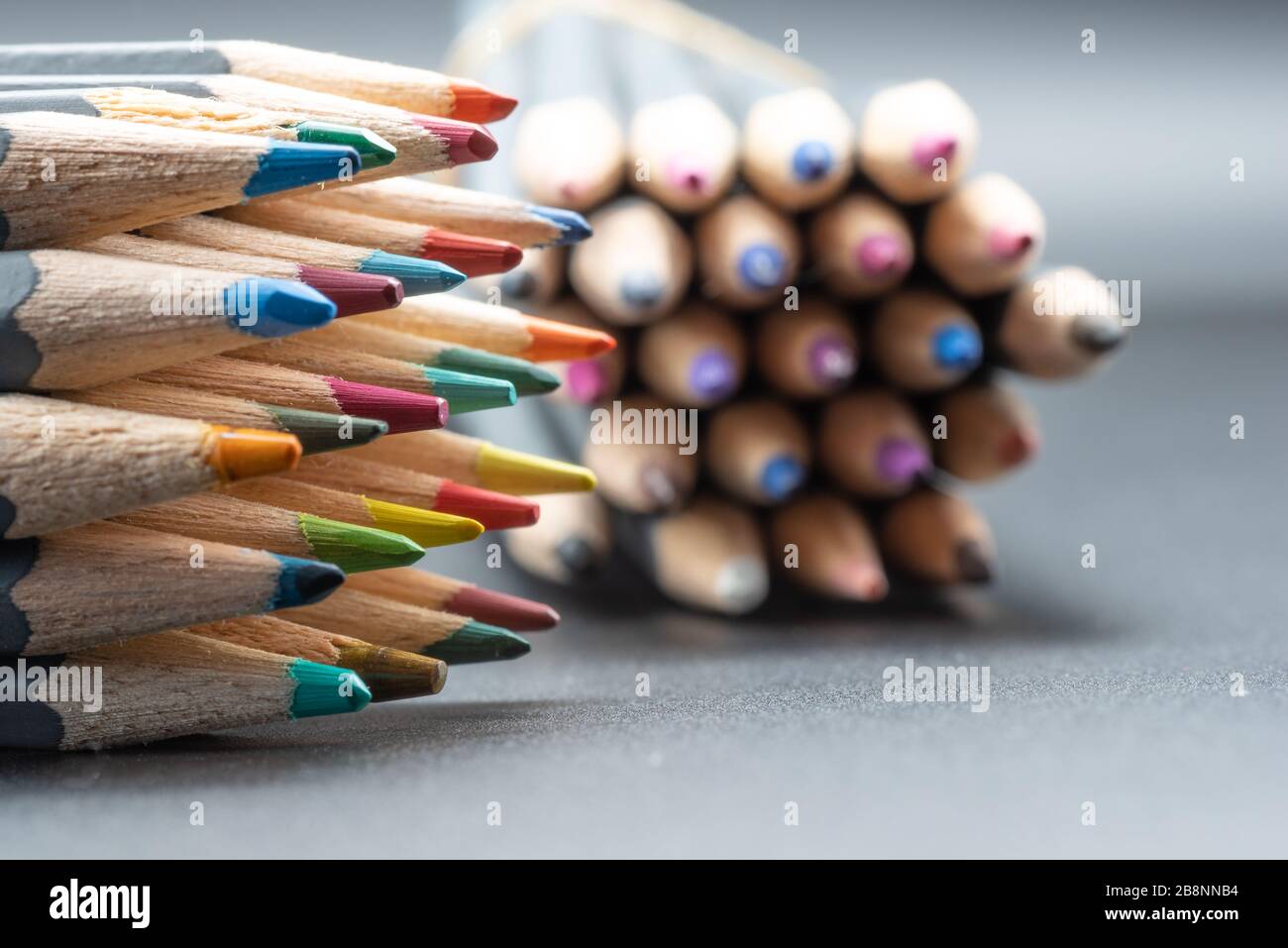 Un'immagine closeup di un mazzo di matite colorate su uno sfondo grigio con spazio per la copia Foto Stock