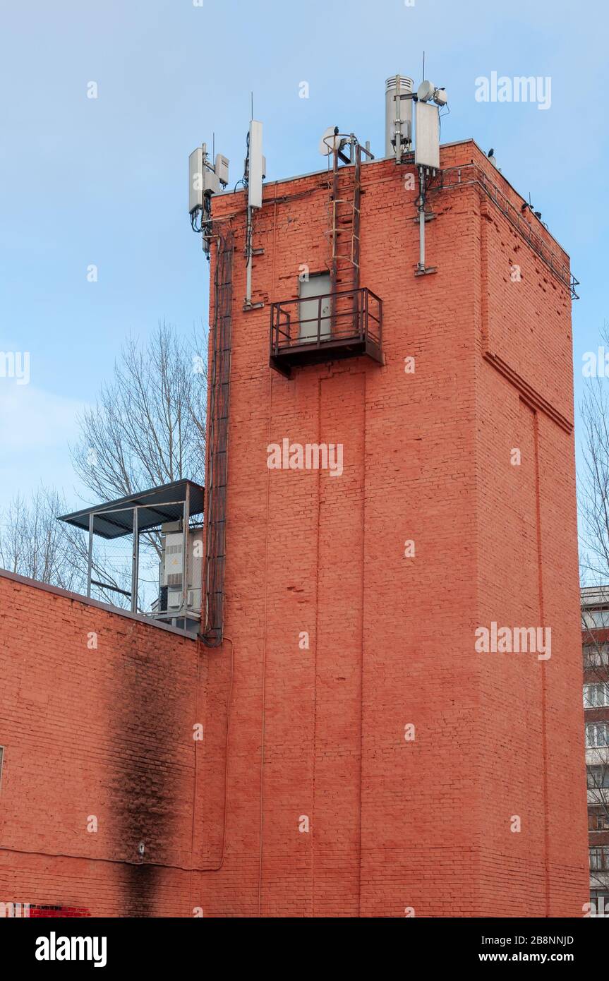 Apparecchiature per la comunicazione cellulare e la trasmissione dati. Antenne 2G, 3G, 4G, 5G installate sul tetto di una vecchia torre d'acqua in mattoni Foto Stock