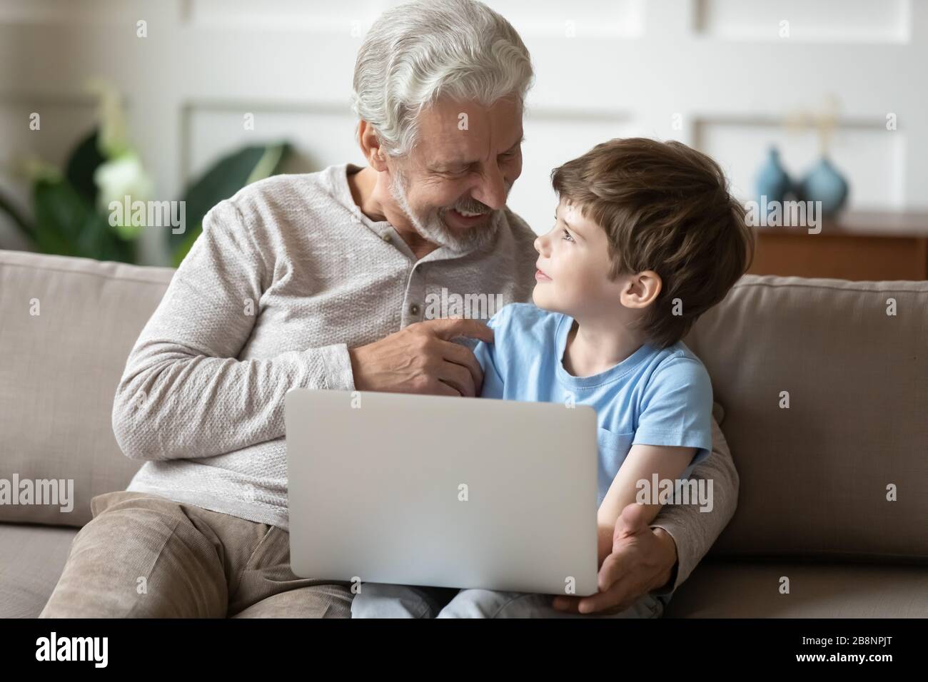 Nonno anziano e nipote in età prescolare che utilizzano il computer portatile insieme Foto Stock