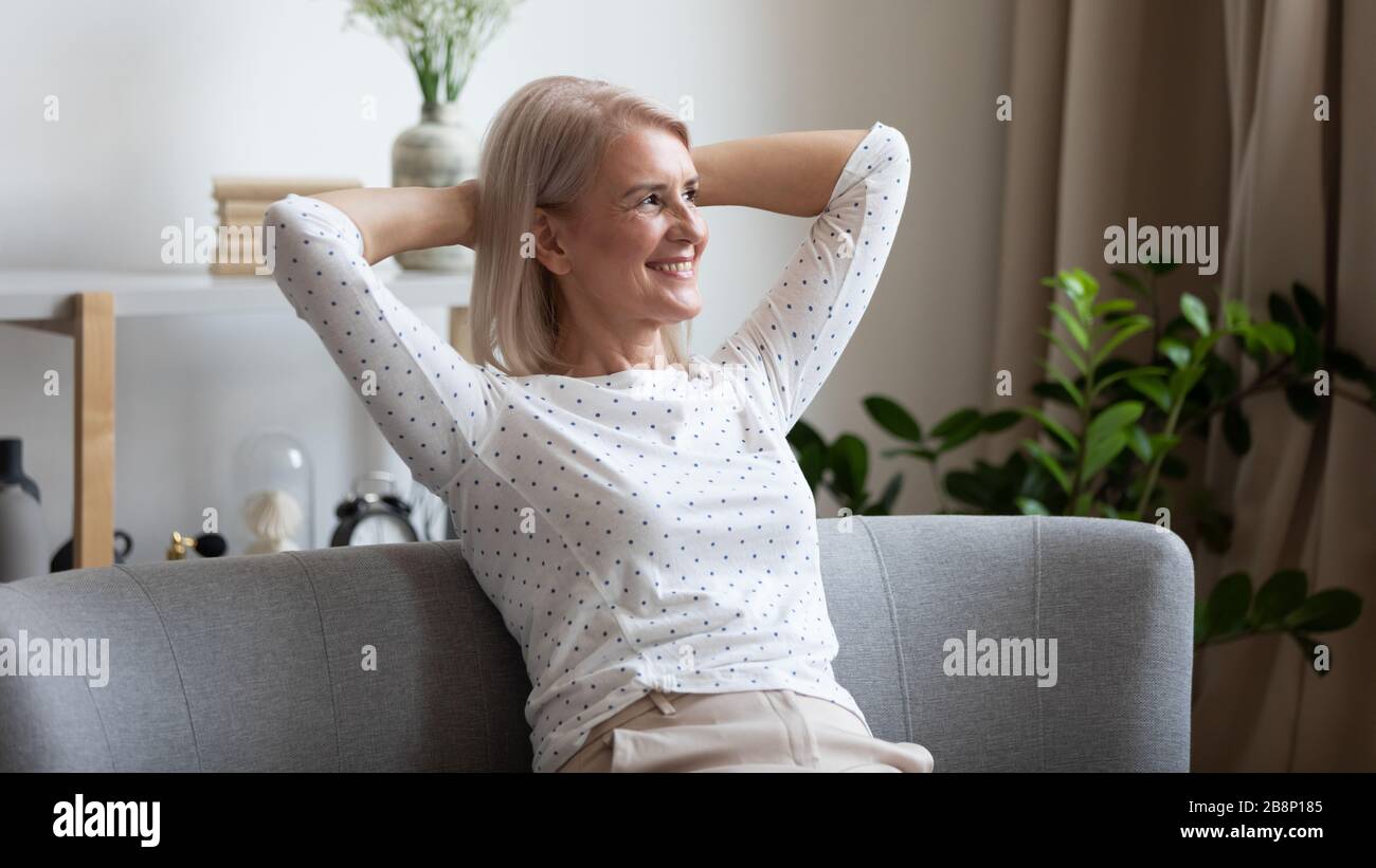 Piacevole donna di mezza età sorridente che si rilassa su un pullman accogliente. Foto Stock