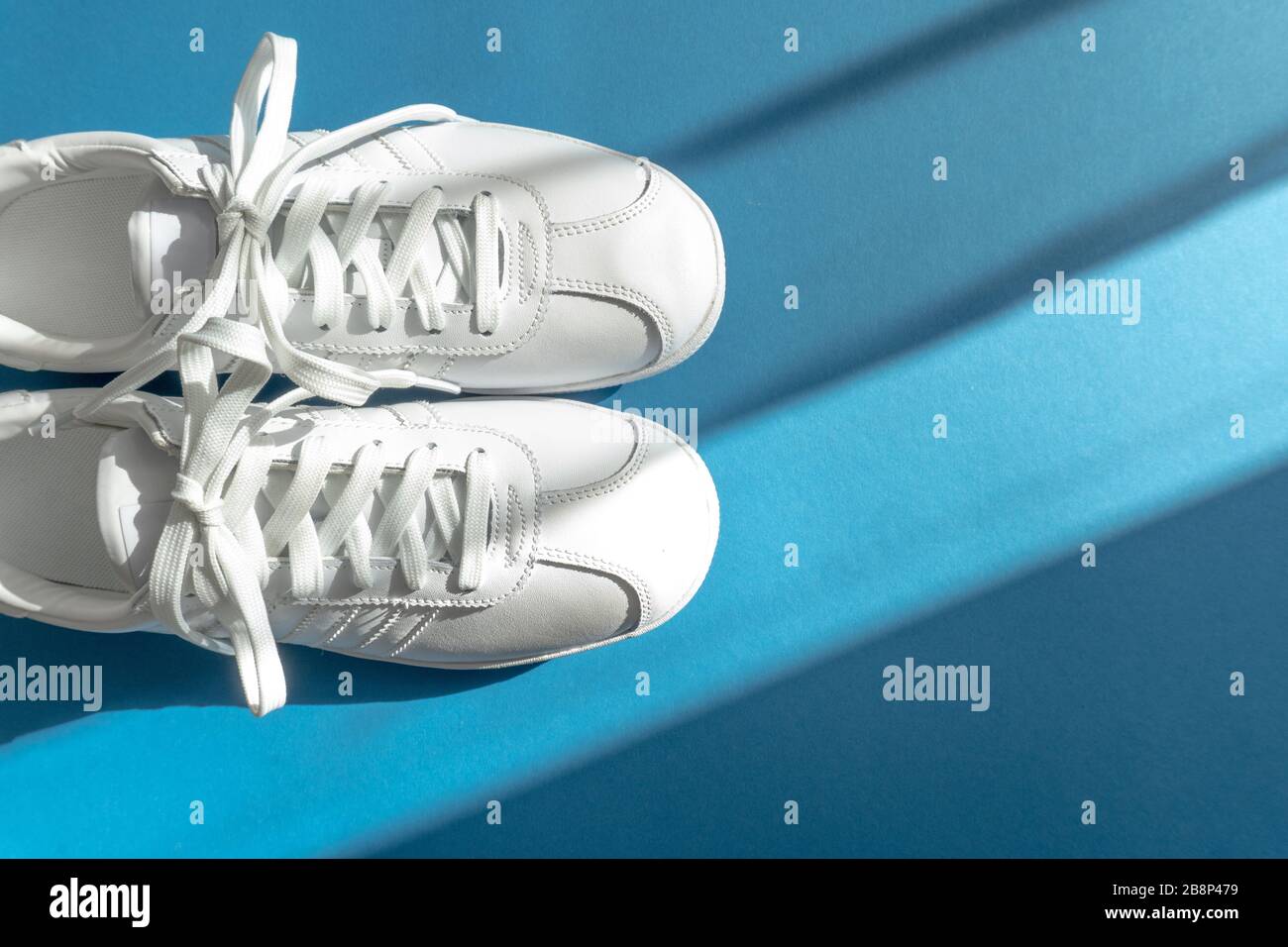 Sneaker bianche unisex su classico sfondo blu Foto Stock