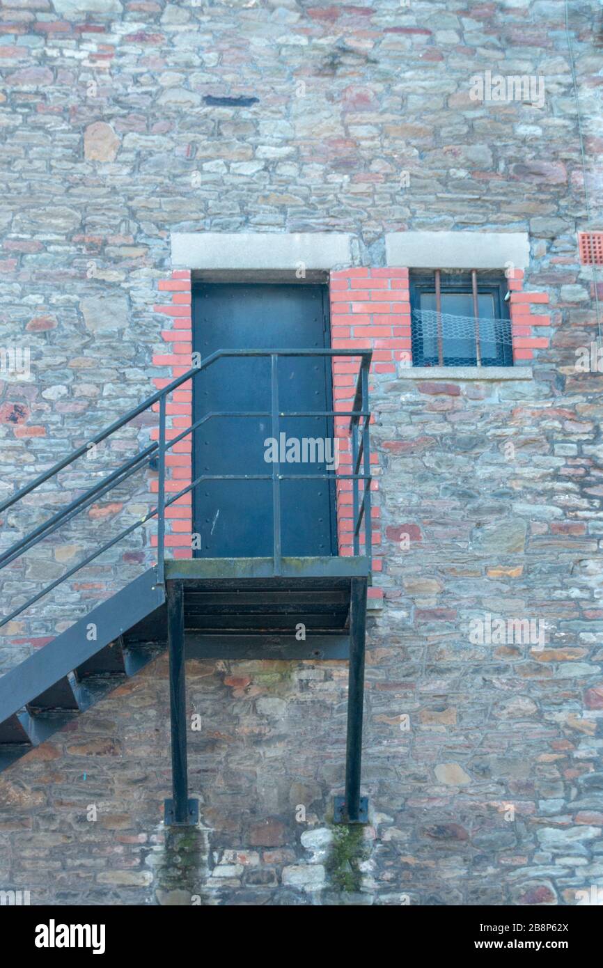 una vista ravvicinata di una scala metallica che porta a una porta nera sul lato di un edificio Foto Stock