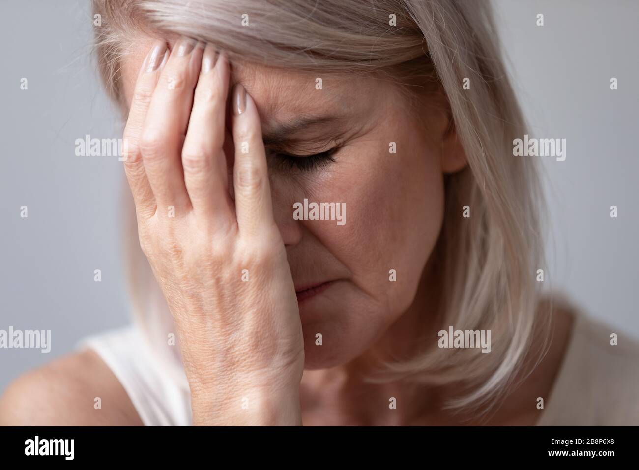 Malsana donna di mezza età che tocca la fronte. Foto Stock