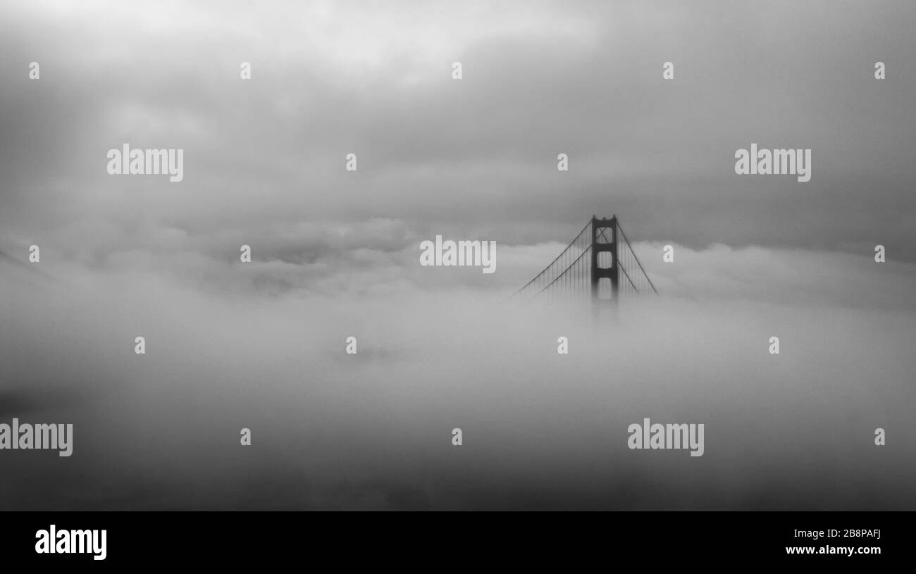 Una torre del Golden Gate Bridge visibile nelle nuvole circostanti, San Francisco, California, Stati Uniti, Nord America, bianco e nero Foto Stock