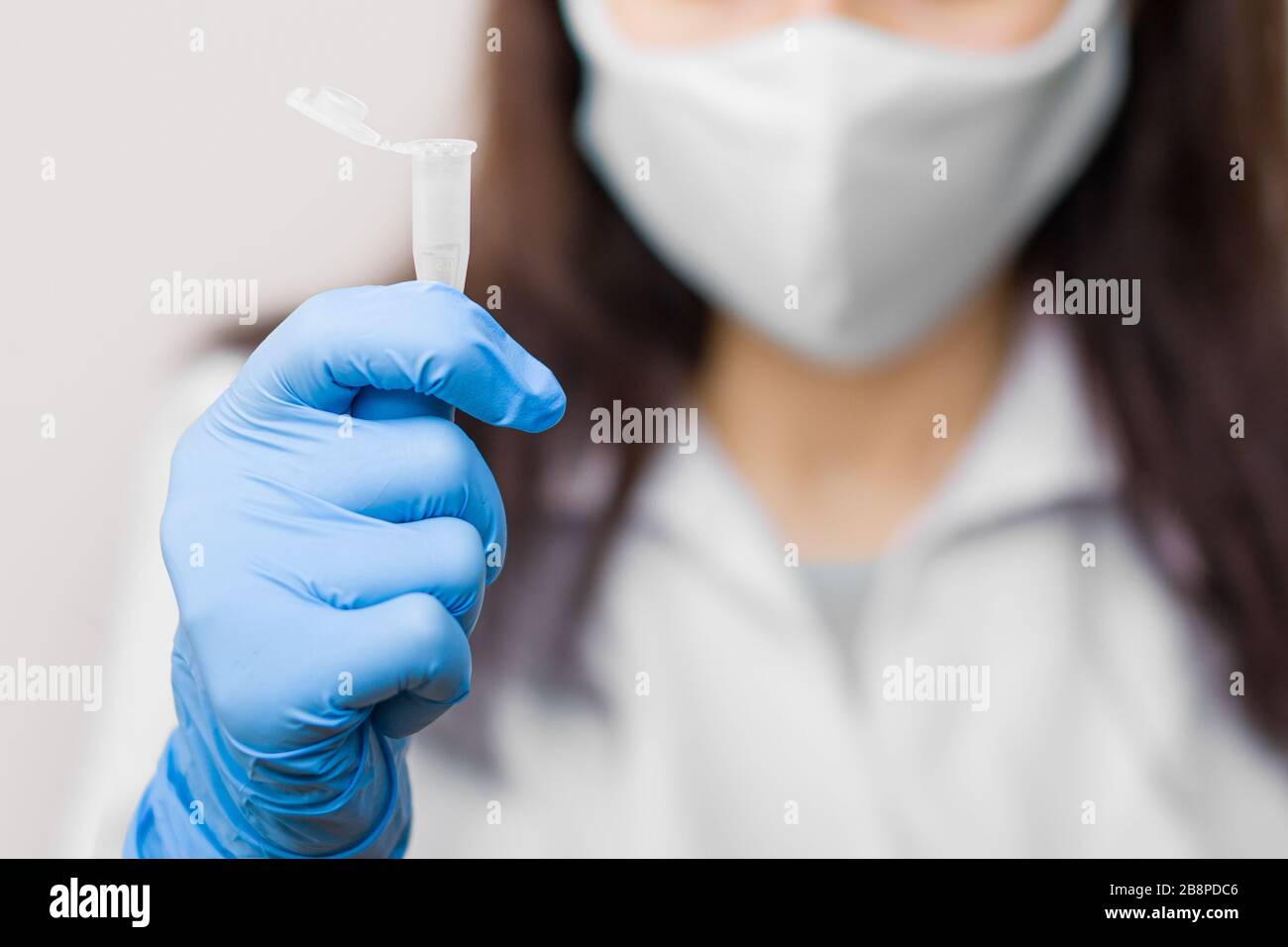 Provetta con sonda su coronavirus, influenza, 2019-nCoV, SARS-nCov, COVID-2019 in donne mani. Medico, indossando guanti blu e maschera protettiva sul Foto Stock