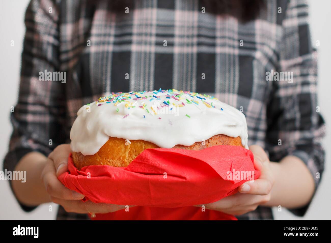 Tradizionale torta di Pasqua in mani femminili. Pane di Pasqua con crema bianca e decorazione colorata sulla parte superiore. Concetto di menu. Foto Stock