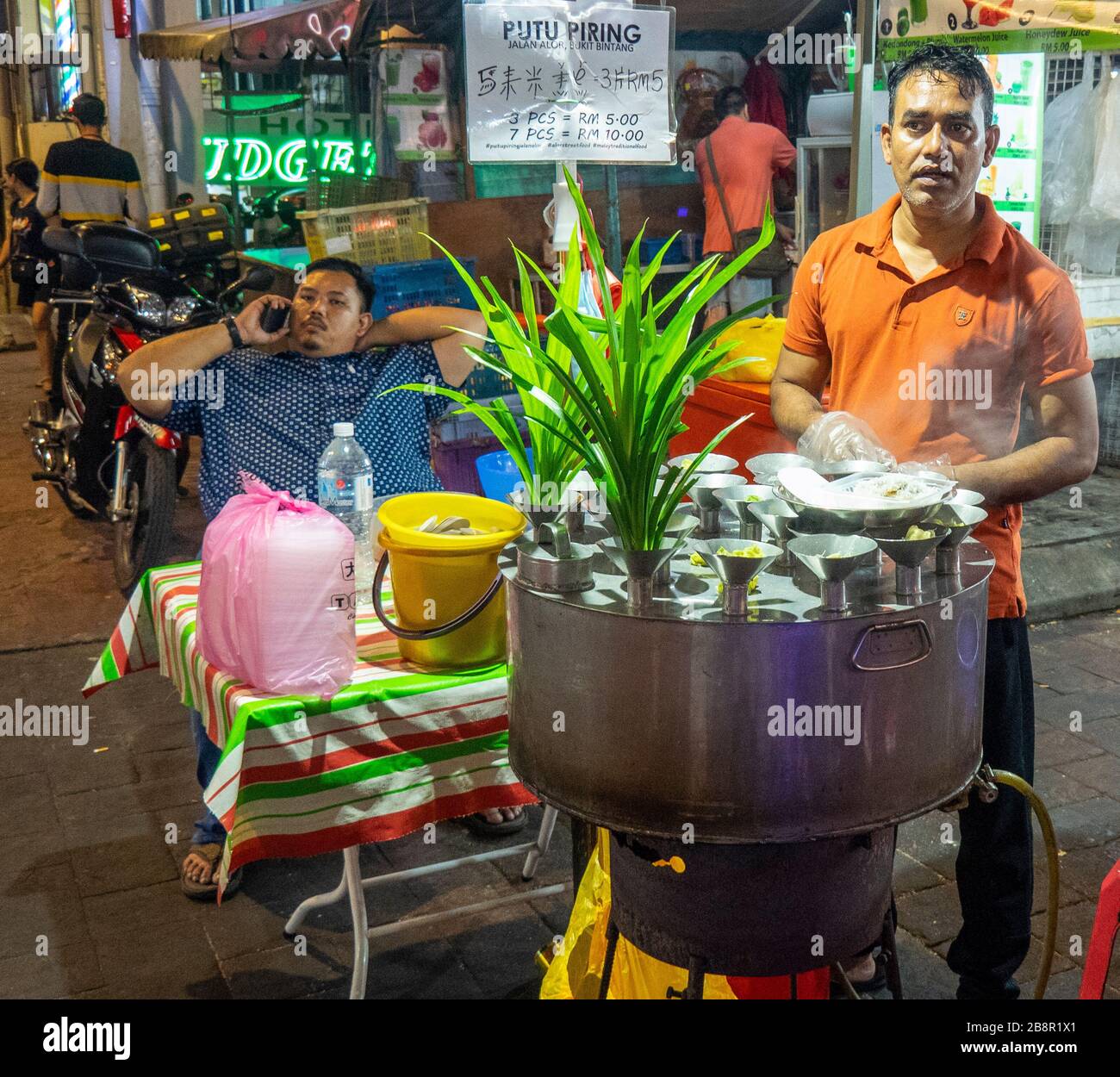 Carrello a vapore e stampi in acciaio inox per preparare putu dolci da dessert in stalle di cibo a Jalan Alor Bukit Bintang Kuala Lumpur Malesia. Foto Stock