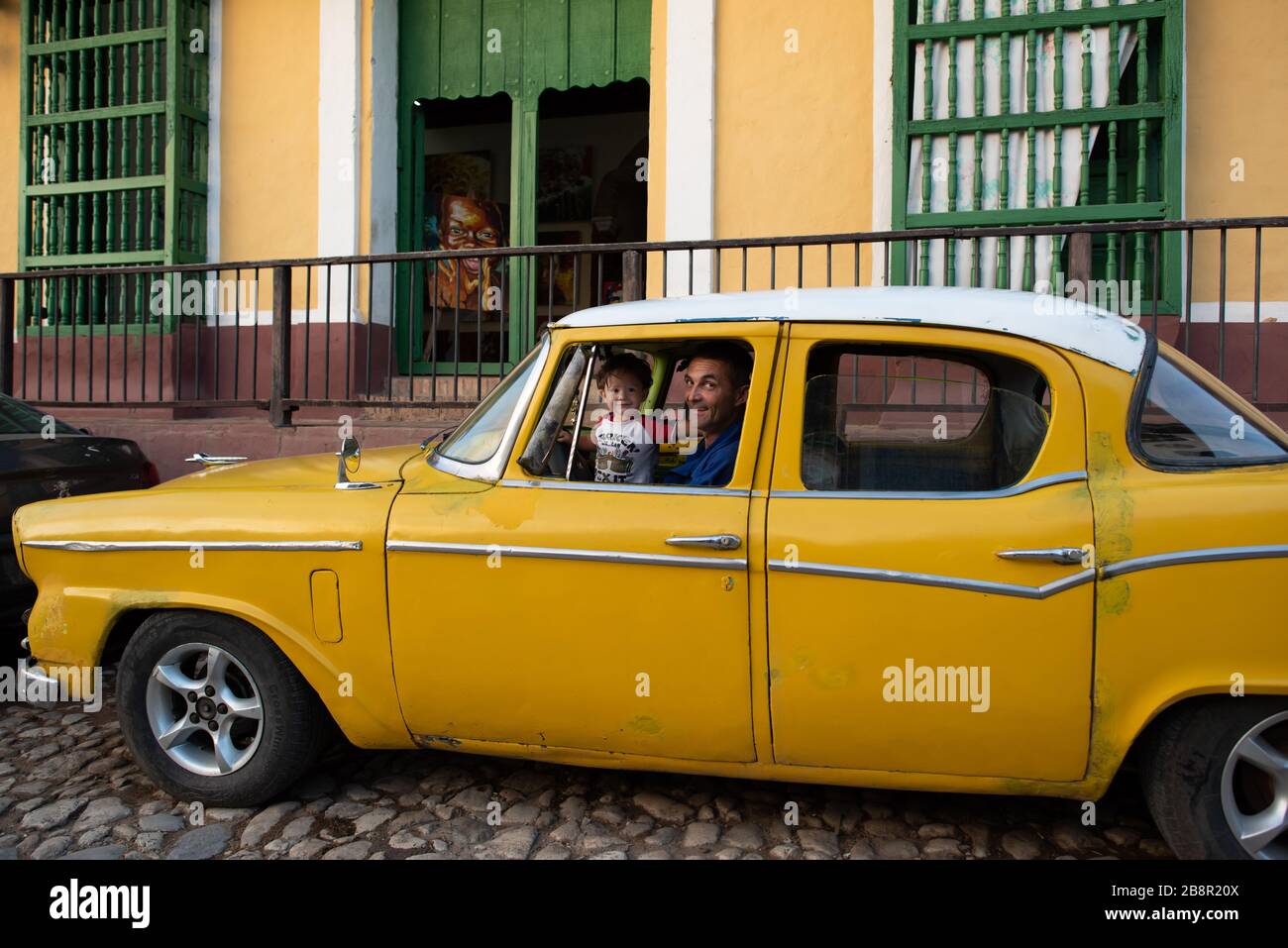 Padre con bambino in macchina gialla n.2, Havana, Cuba Foto Stock