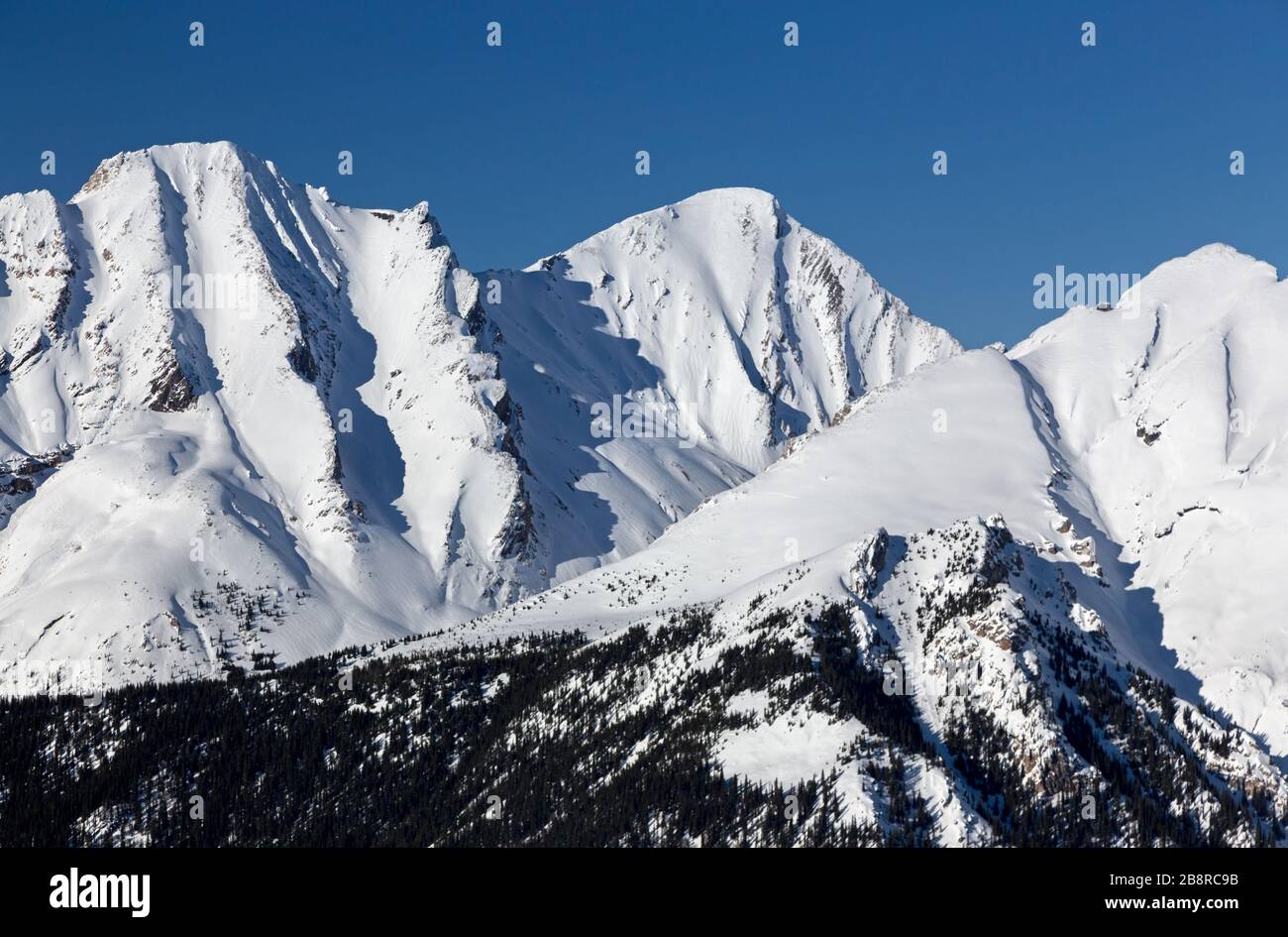 Rocky Mountain Peaks Ridge innevata. Paesaggio panoramico del Parco Nazionale di Banff. Soleggiata giornata invernale, skyline blu delle Montagne Rocciose canadesi Foto Stock