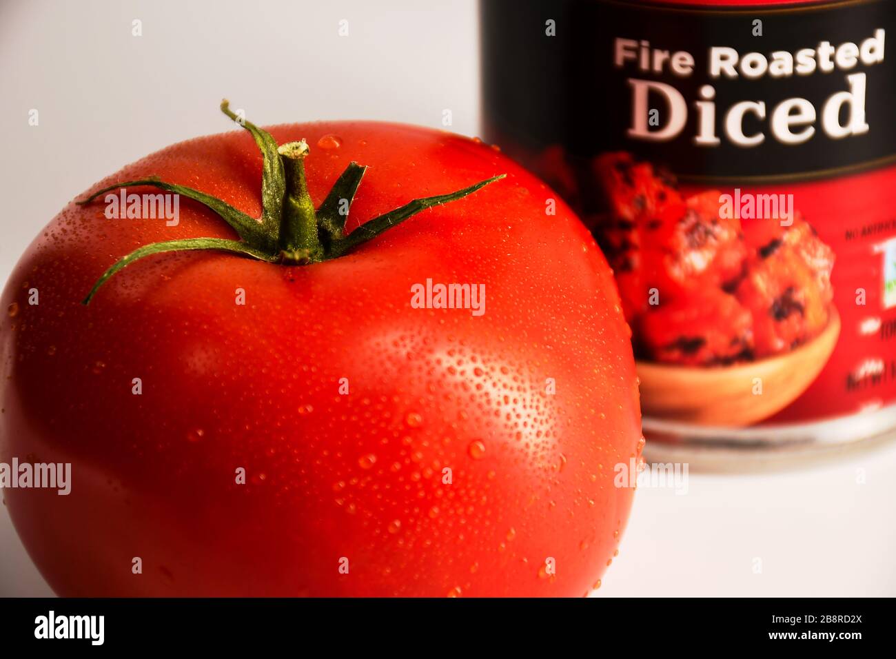 studio primo piano di pomodoro rosso con lattina di pomodori a dadini sullo sfondo Foto Stock