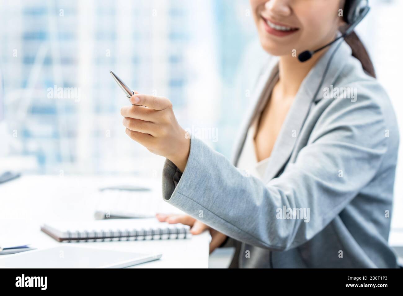 Donna addetto al telemarketing che punta mano mentre lavora in ufficio Foto Stock