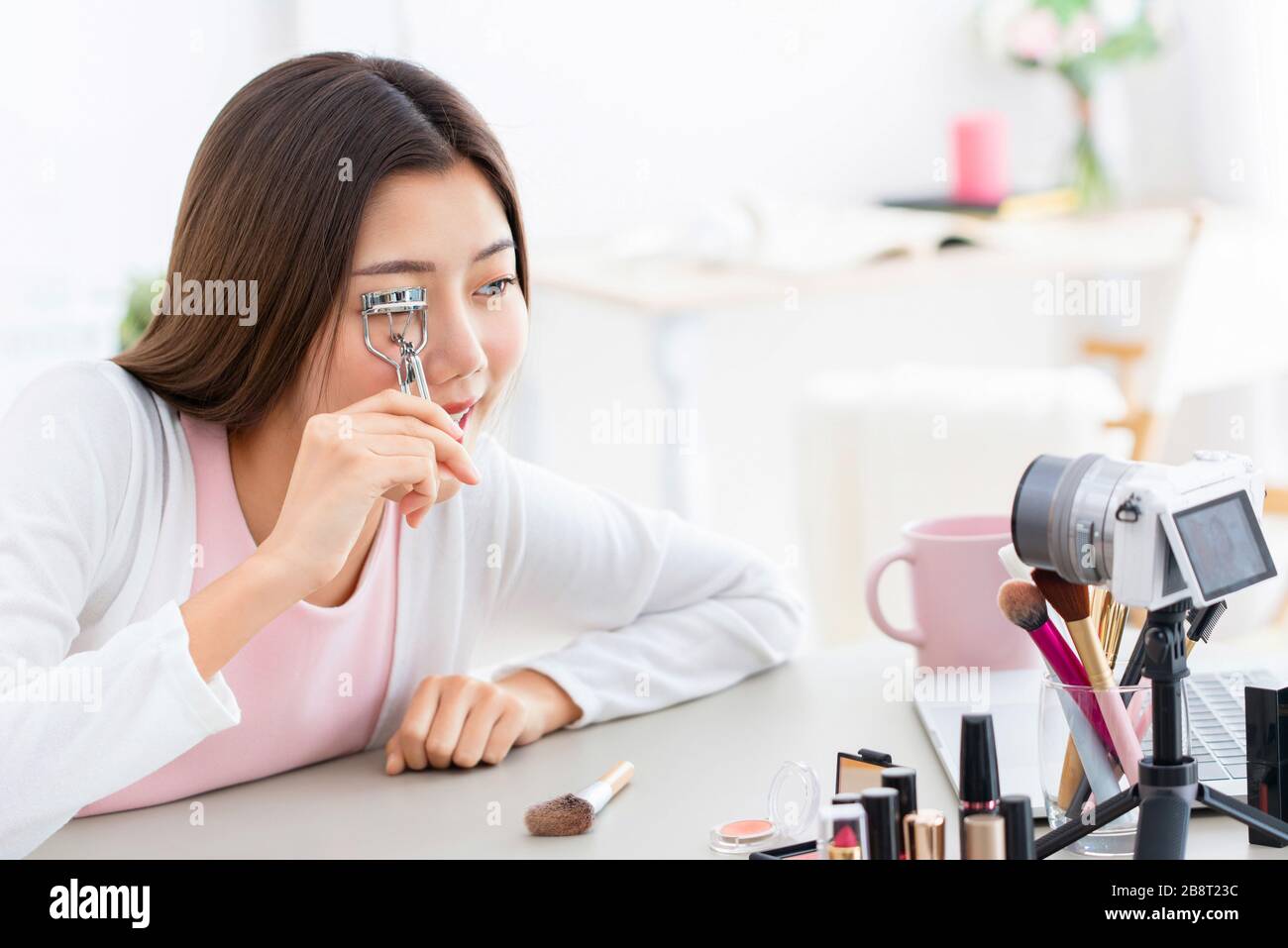 Giovane ragazza asiatica beauty influencer registrare il video mentre si utilizza eyelash arricciatore a casa Foto Stock