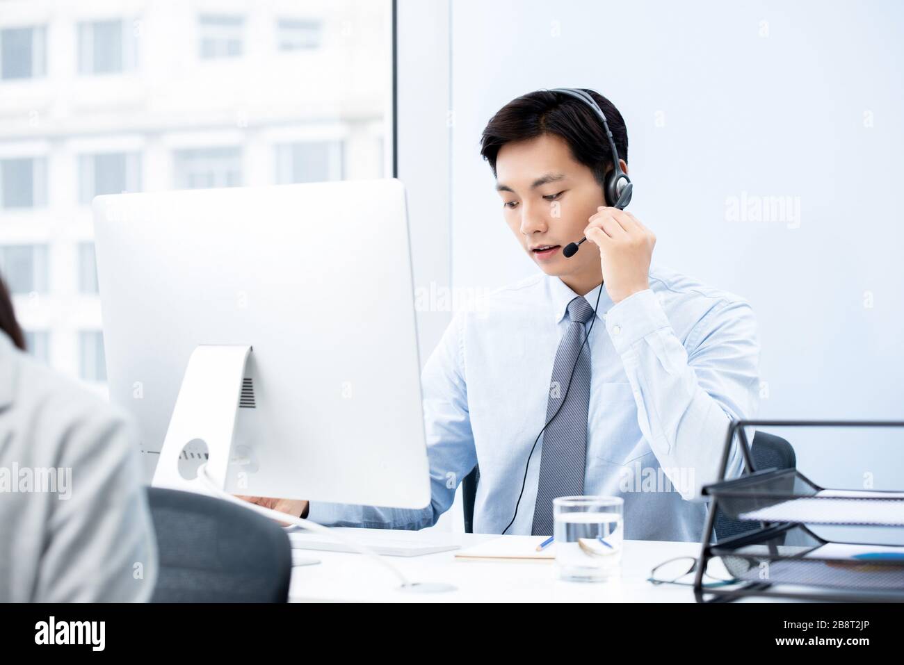 Un bell'uomo asiatico concentrato che lavora nell'ufficio del call center come operatore di telemarketing Foto Stock