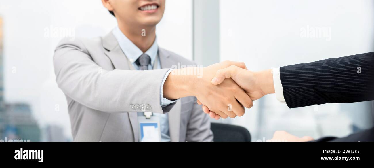 Uomini d'affari che fanno stretta di mano nella sala riunioni in ufficio della città, banner panoramico Foto Stock