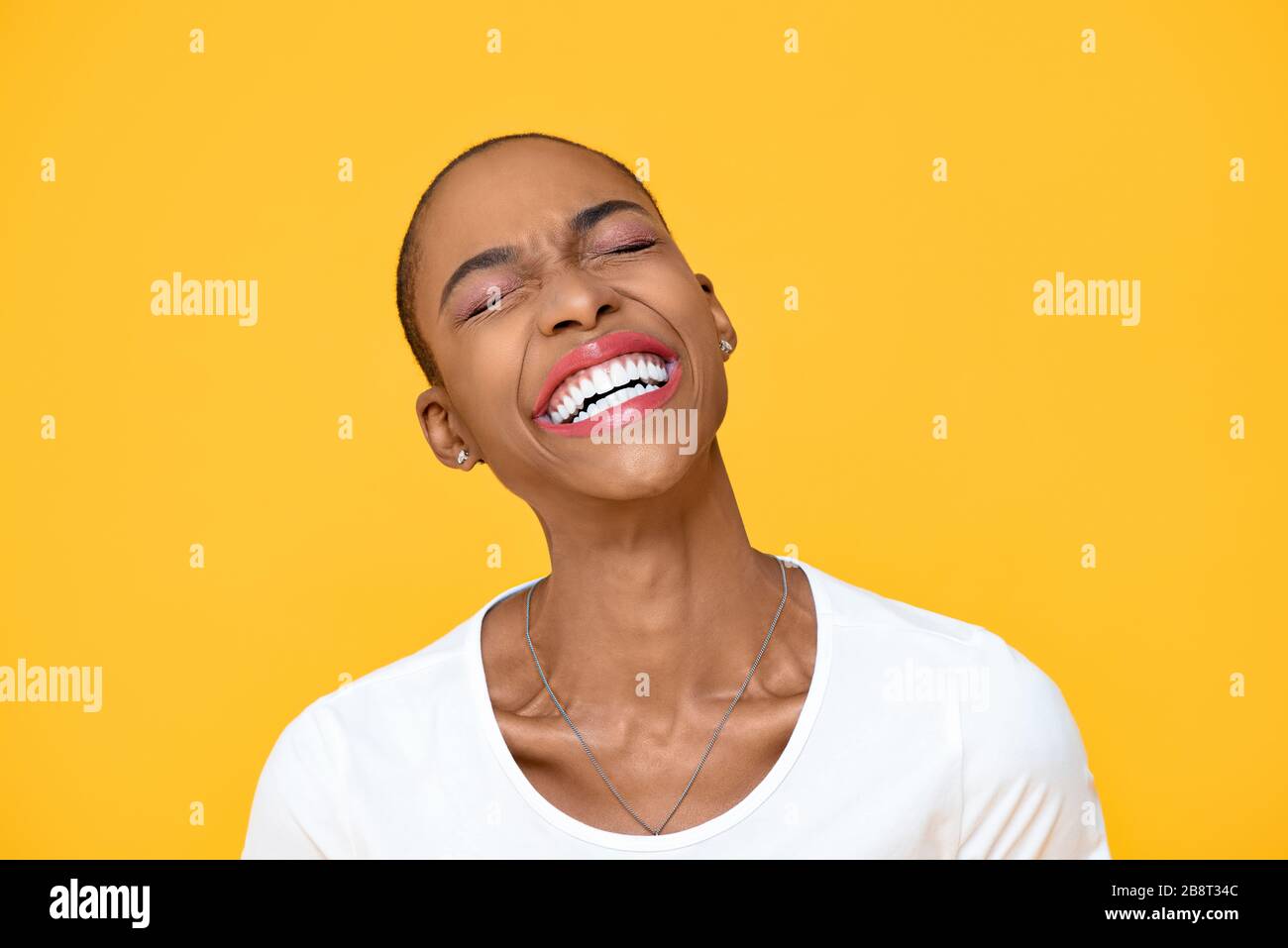 Felice donna afro-americana ottimista ridente con occhio chiuso isolato su sfondo giallo colorato Foto Stock