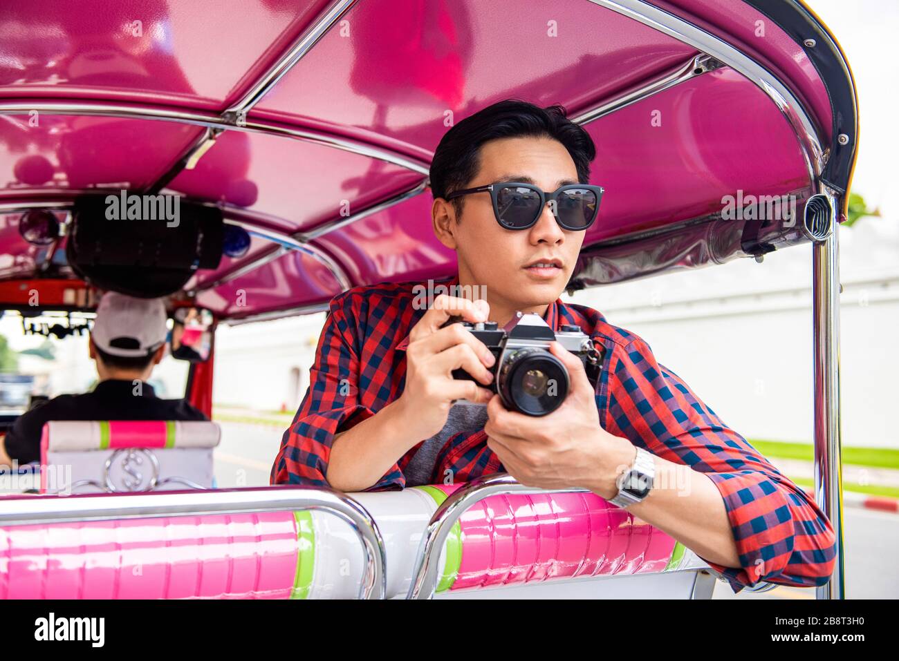 Bel maschio asiatico turistico tenendo macchina fotografica su tuk tuk taxi a Bangkok Thailandia durante le vacanze estive viaggio da solo Foto Stock