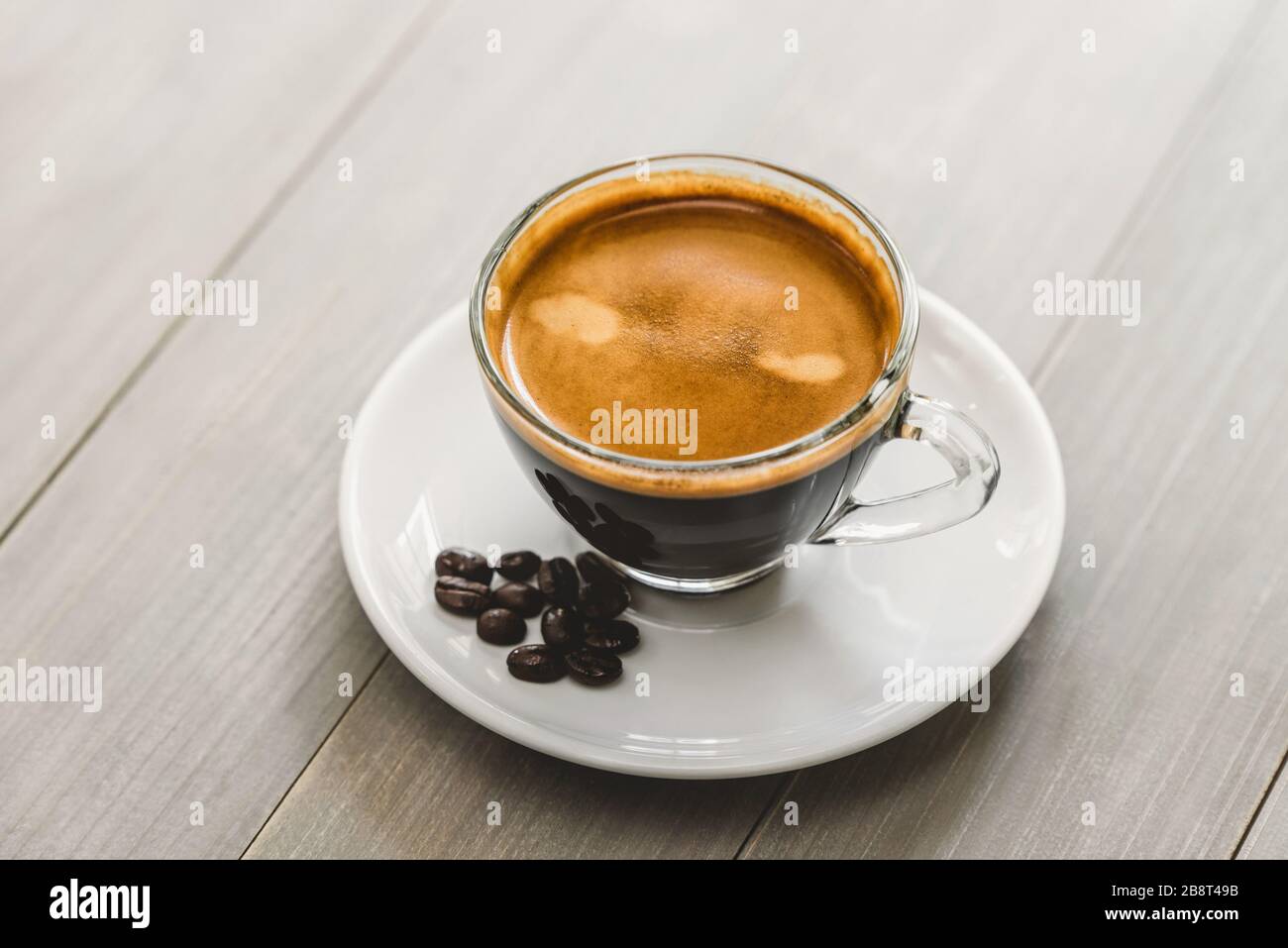 Una tazza calda di caffè espresso preparato su un piattino in un tavolo di legno d'epoca Foto Stock