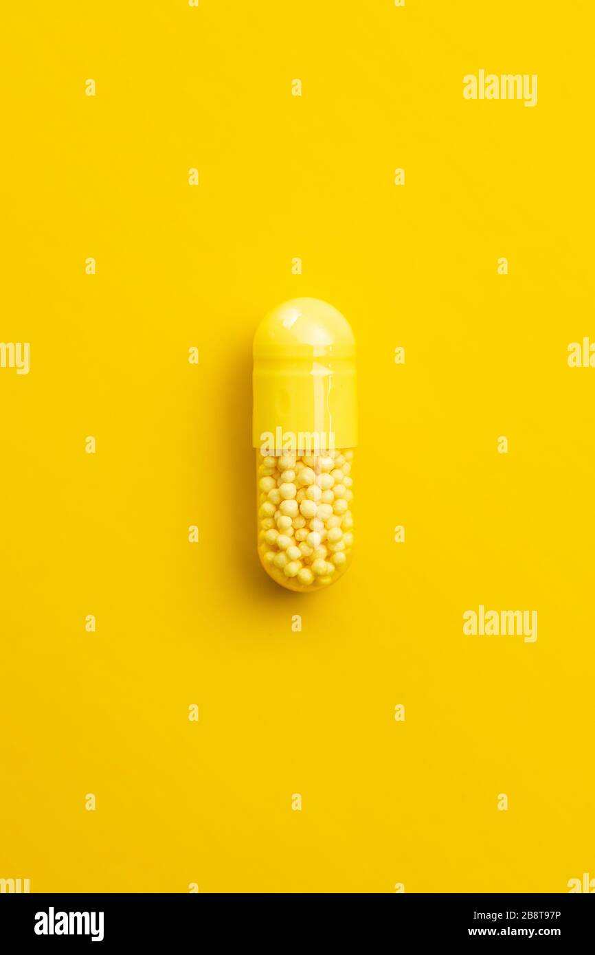 Capsula di vitamina. Pillola di vitamina C su sfondo giallo. Vista dall'alto. Foto Stock