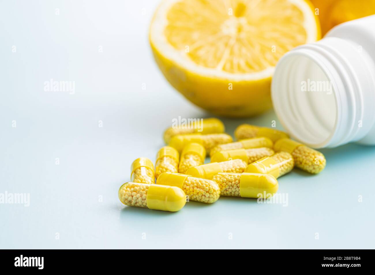 Capsule vitaminiche. Pillole di vitamina C, frutta di limone e bottiglia di pillola su sfondo blu. Foto Stock
