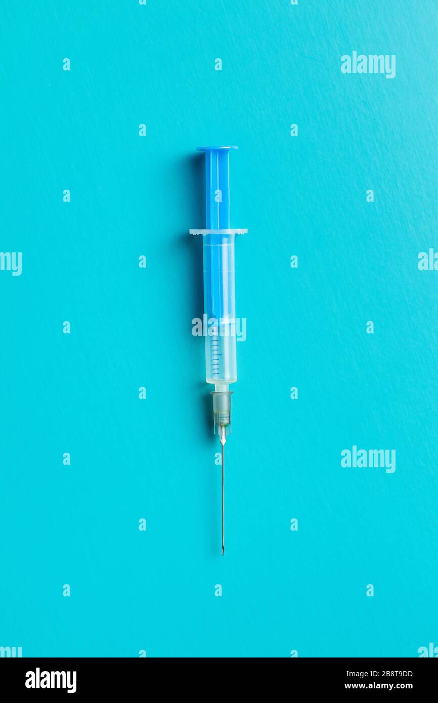 Siringa blu per uso medico su sfondo colorato. Vista dall'alto. Foto Stock