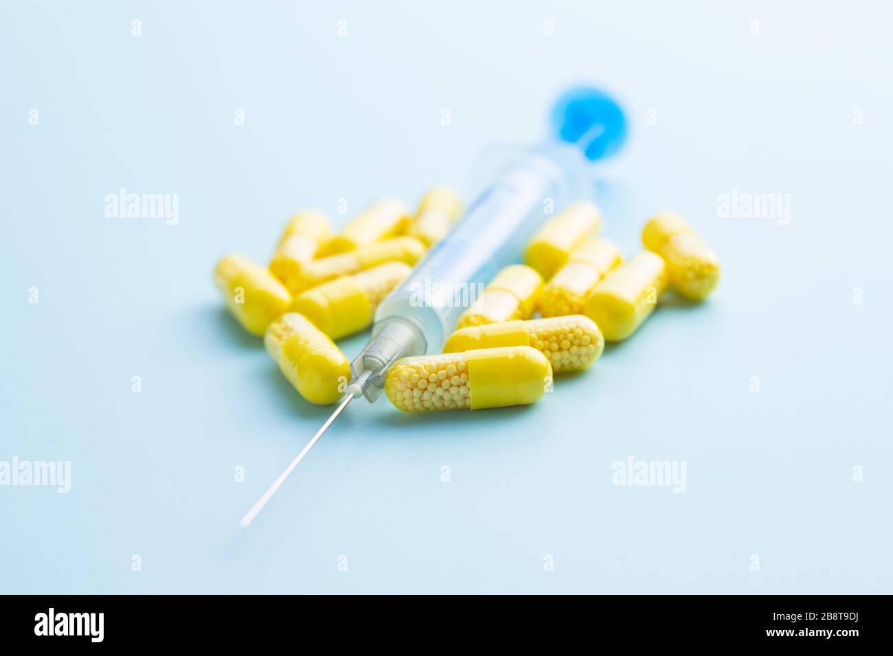 Capsule vitaminiche. Pillole di vitamina C e siringa su sfondo blu. Foto Stock