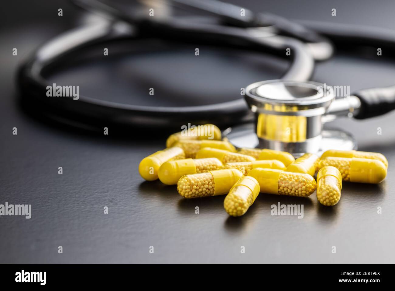 Capsule vitaminiche. Pillole di vitamina C e stetoscopio su sfondo nero. Foto Stock