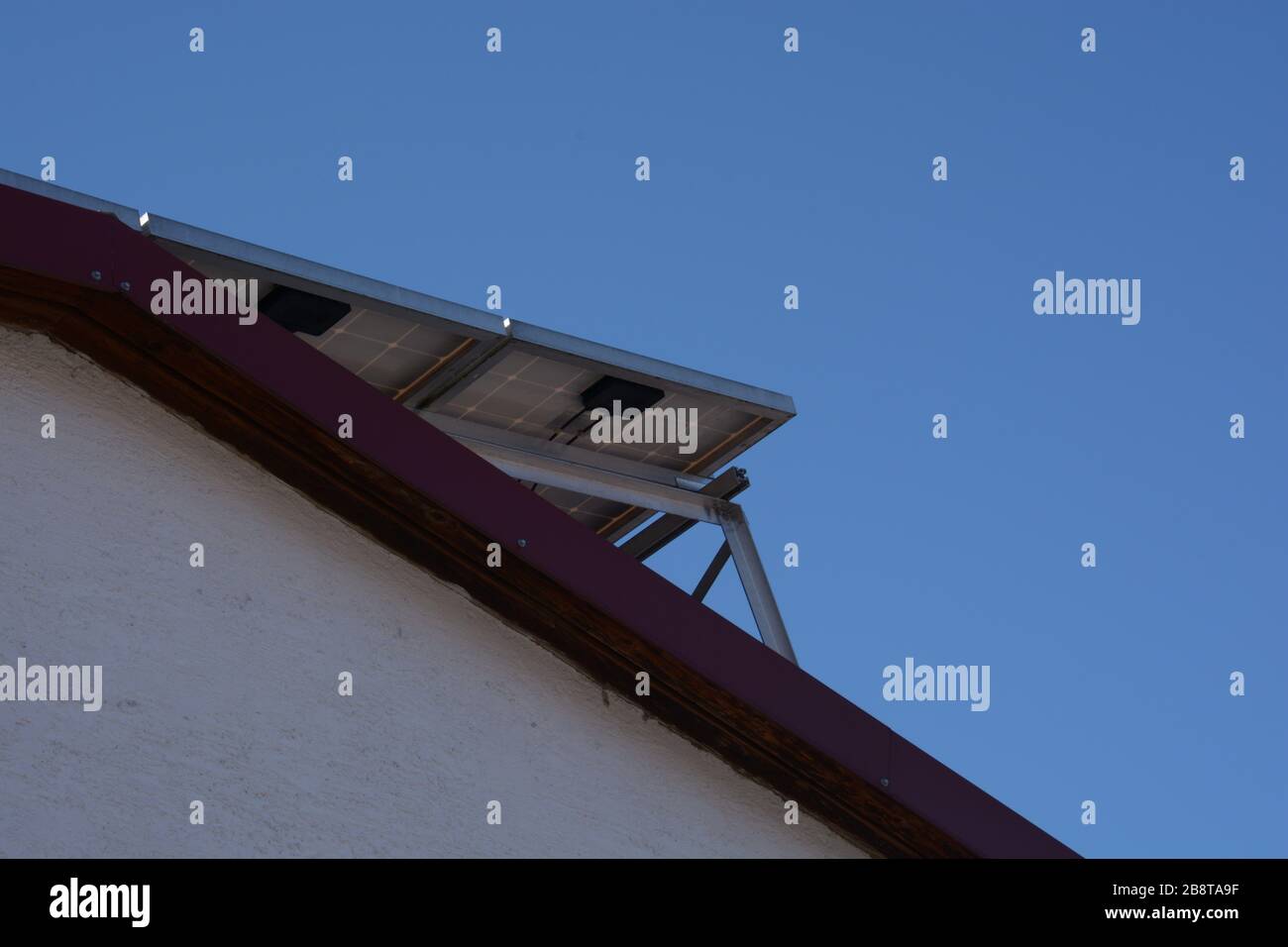 installazione del pannello solare sul tetto con sfondo blu trasparente, pannello fotovoltaico visto dal basso sul tetto Foto Stock