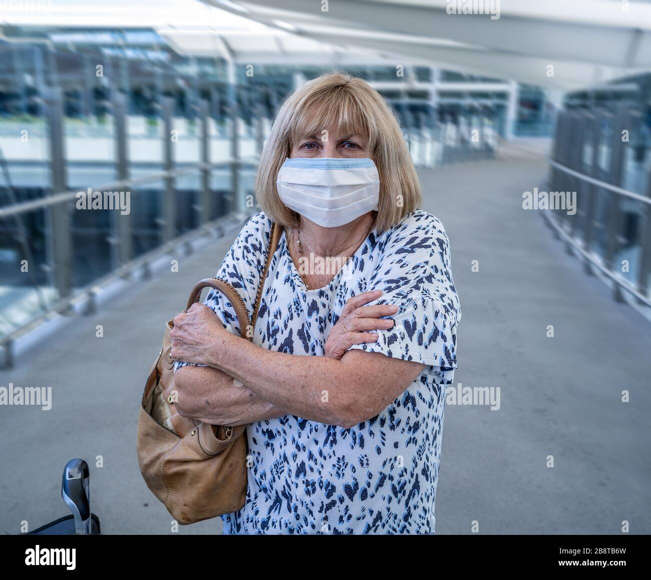 Divieto e restrizioni di viaggio per l'epidemia di coronavirus. Viaggiatore con maschera facciale all'aeroporto internazionale interessato dalla cancellazione del volo. COVID-19 pande Foto Stock