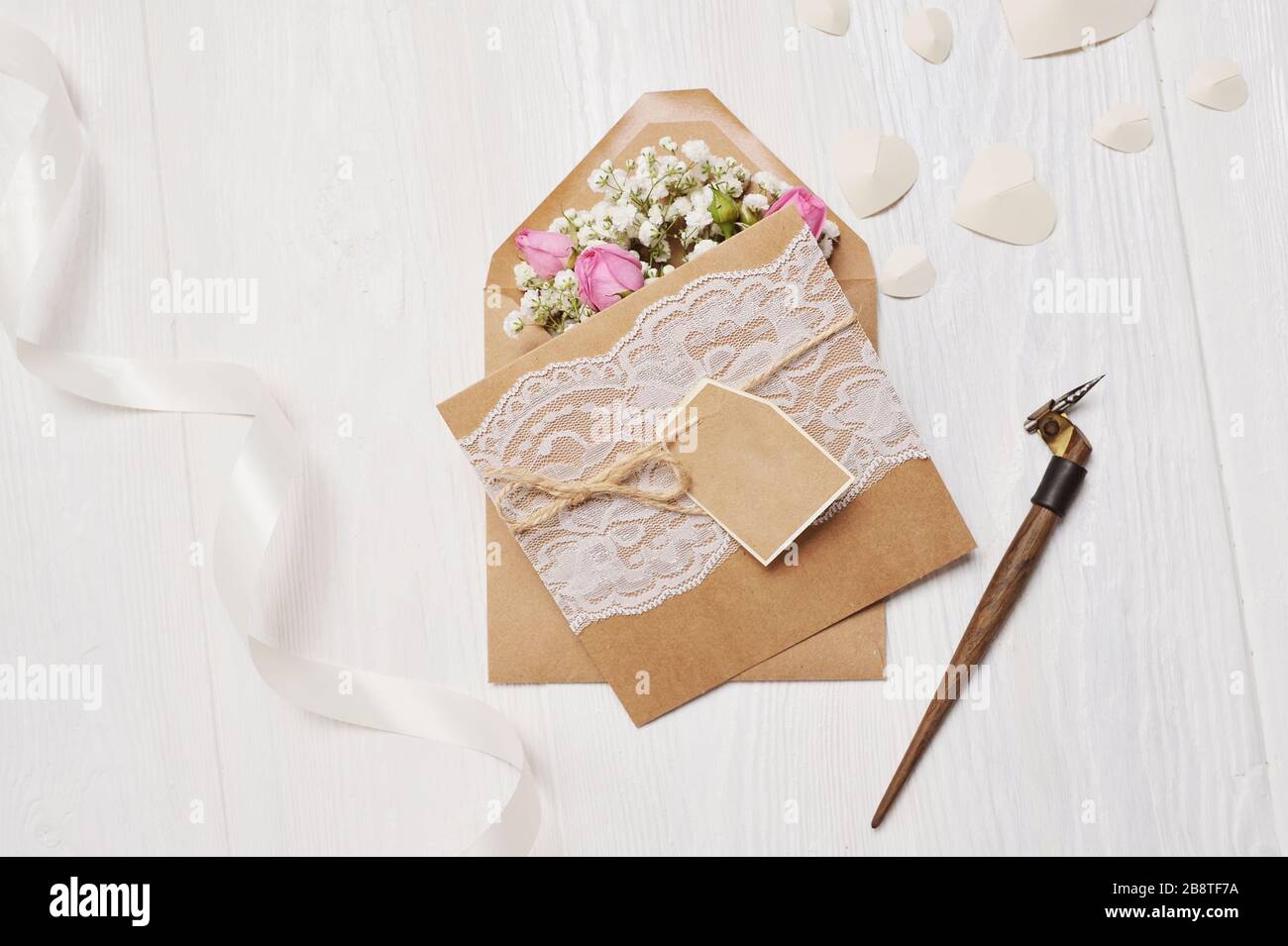 Piuma calligrafica una busta con fiori e una lettera, biglietto di auguri per San Valentino con posto per il tuo testo. Mock foto con disposizione piatta e vista dall'alto Foto Stock