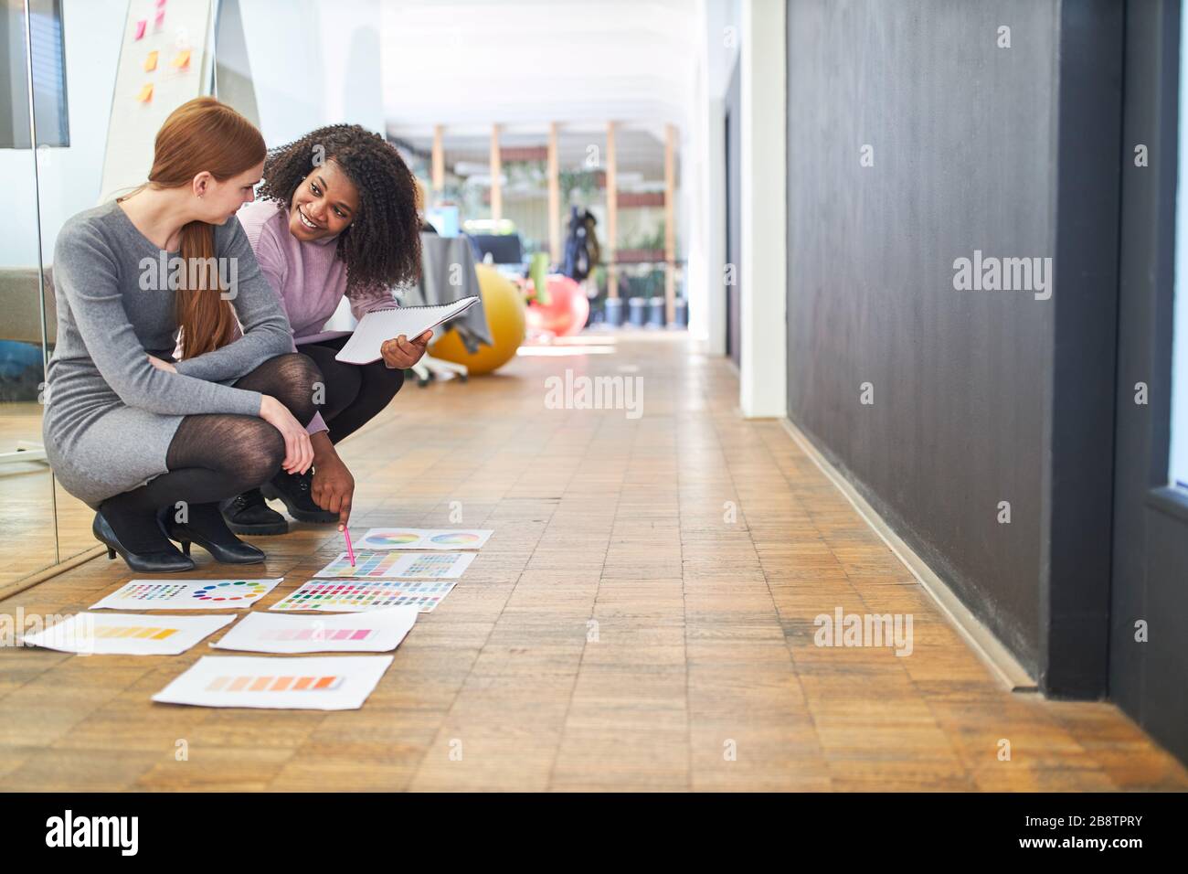 Due giovani donne come designer grafici controllano la prestampa per il design dei colori Foto Stock