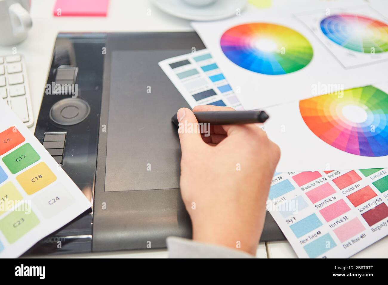 Mano di un grafico in design a colori con penna e tavoletta e ruota dei colori Foto Stock