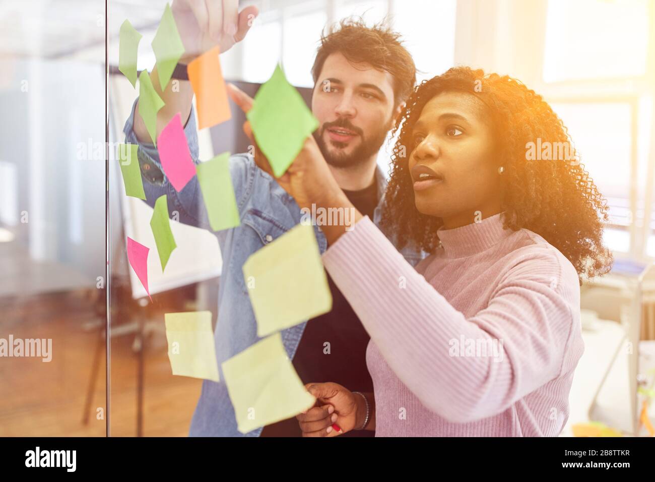 Brainstorming creativo in ufficio con note appiccicose su una parete di vetro Foto Stock