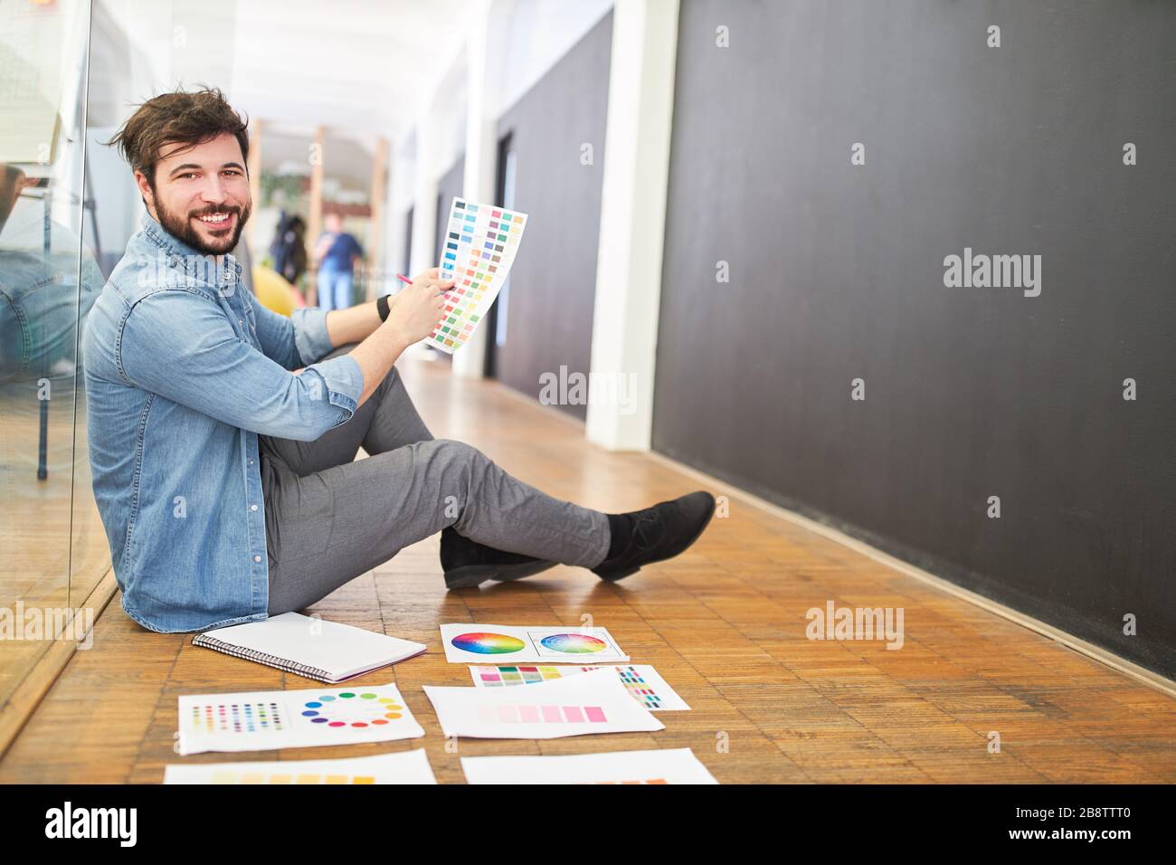 Designer grafico soddisfatto nella selezione dei colori con tavolozza dei colori nell'agenzia di design Foto Stock