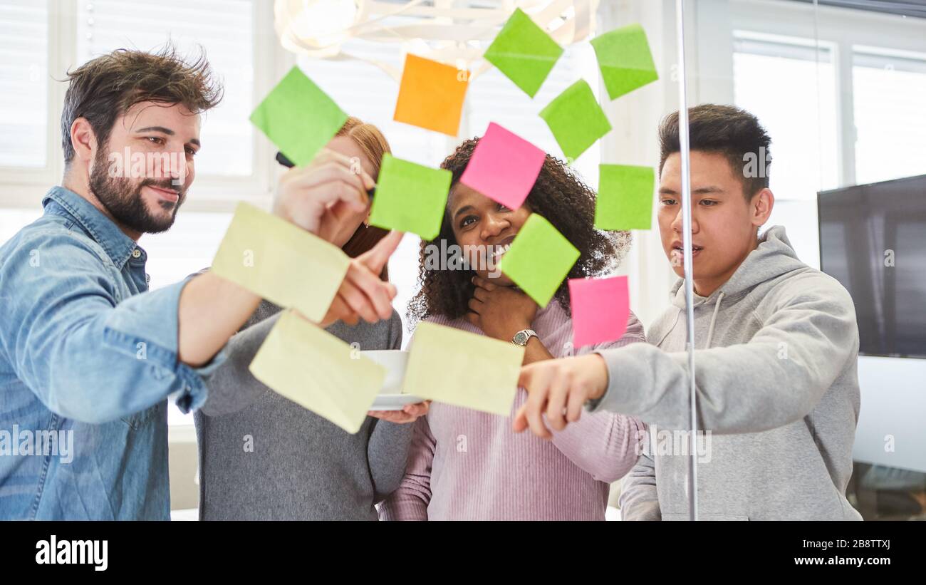 Avviare il team in un workshop creativo di brainstorming con note adesive durante la valutazione Foto Stock