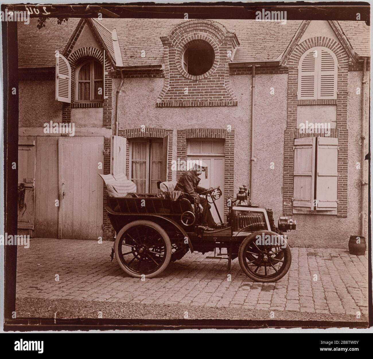 Uomo che guida una macchina di fronte a una casa. 'Homme au volant d'une voiture devant une maison'. Anonima fotographie. Aristotipo. Parigi, musée Carnavalet. Foto Stock