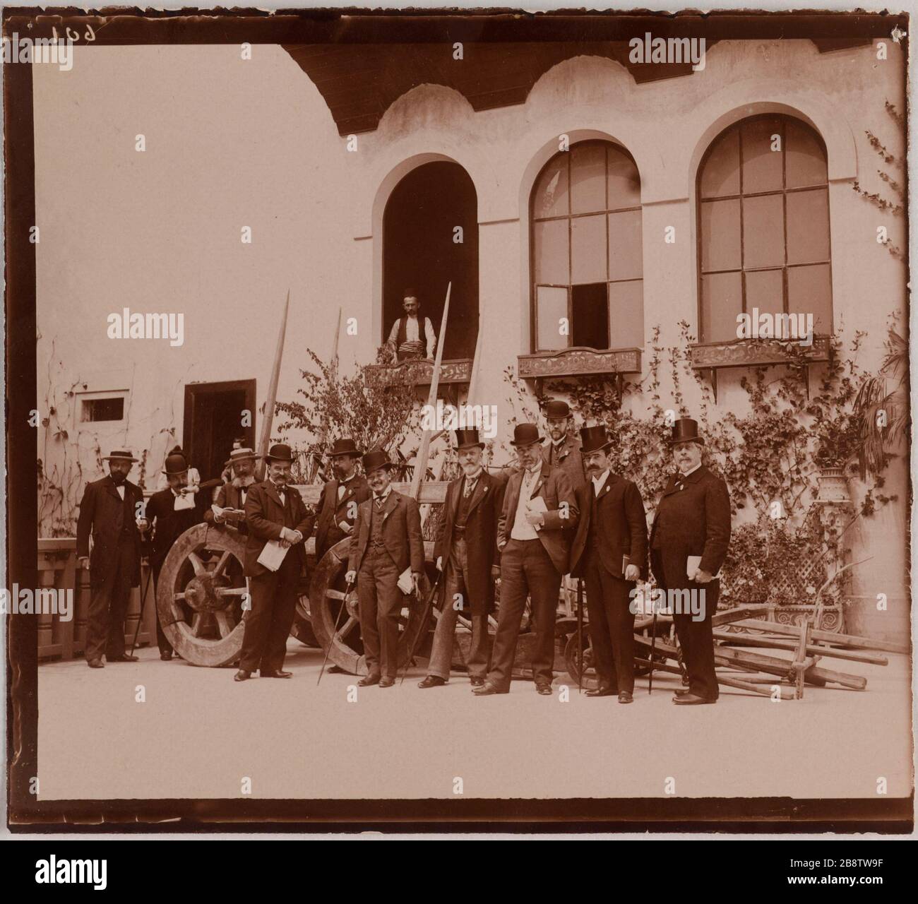 World Expo 1900, rue des Nations, il Quai d'Orsay. Trolley in legno accanto alla bandiera della Bosnia con persone in posa di fronte, bandiera Perù visibile in fondo, nella strada delle Nazioni, Parigi. Esposizione universelle de 1900. "Chariot en bois à côté du pavillon de la Bognie avec personnes posant devant, pavillon du Pérou visible au fond, dans la rue des Nations, Paris". Anonima fotographie. Aristotipo. 1900. Parigi, musée Carnavalet. Foto Stock