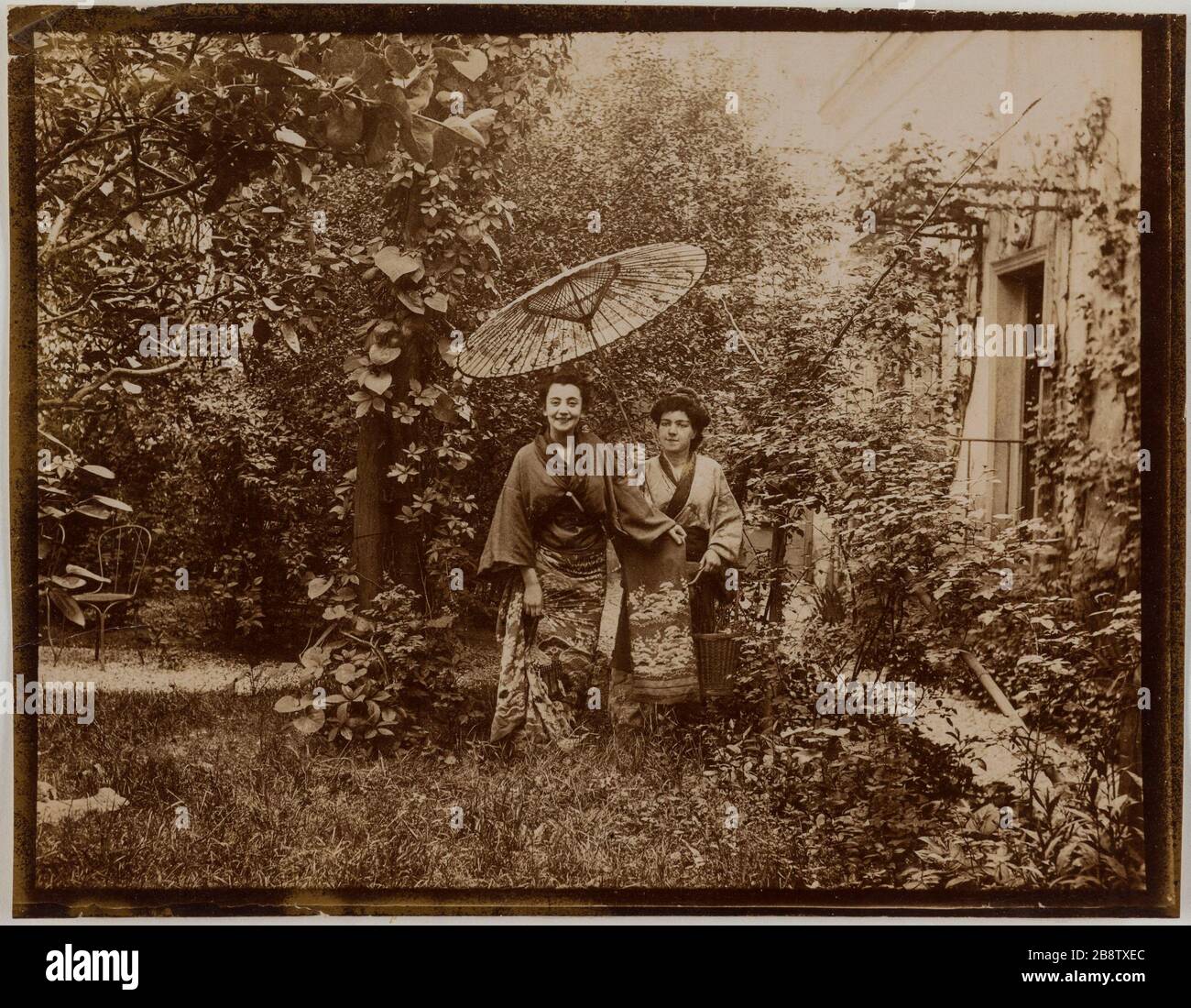 Coppia attrici in kimono con ombrello in un giardino vicino a casa. Couple d'actrices en kimonos avec ombrelle, dans un jardin près d'une maison. Anonima fotografa, vers 1900. Parigi, musée Carnavalet. Foto Stock