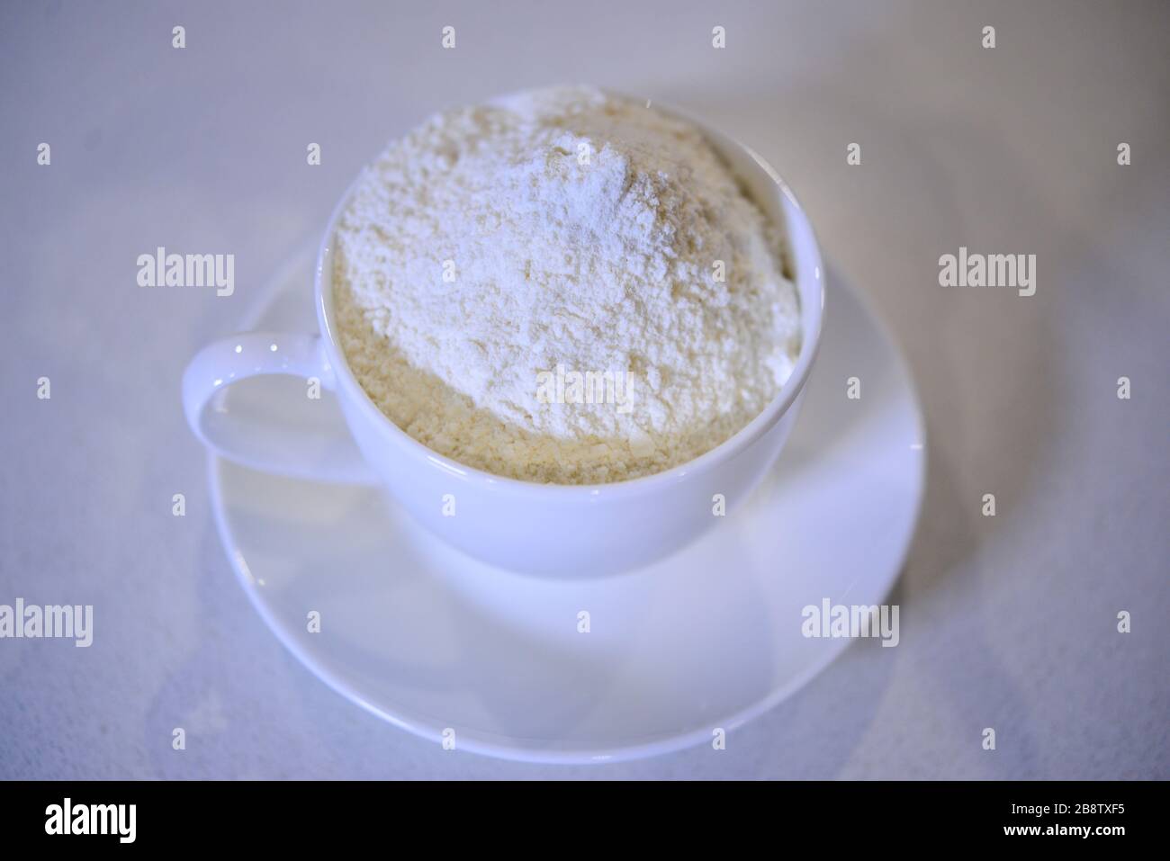 Tazza e Saucer di cottura traboccante di farina a casa in isolamento di auto Foto Stock