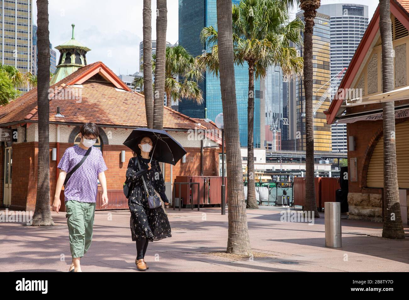 Centro di Sydney, Australia. Lunedì 23 Marzo 2020. Una coppia asiatica che indossava maschere facciali al Circular Quay il giorno i ristoranti e i bar venivano ordinati per chiudere in tutta l'Australia. Credit Martin Berry/Alamy Live News Foto Stock