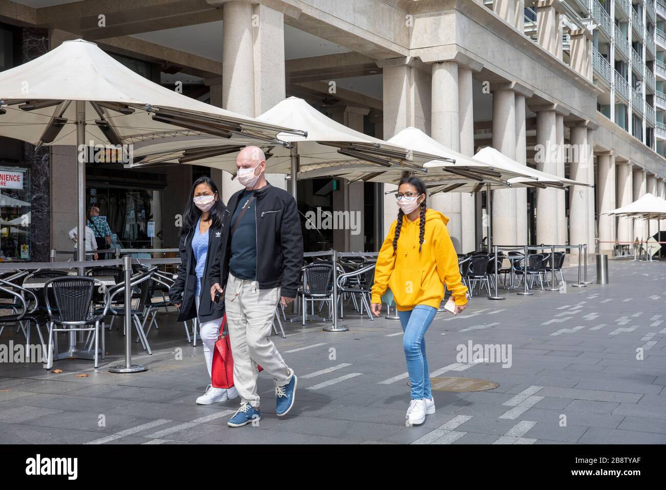 Centro di Sydney, Australia. Lunedì 23 Marzo 2020. La famiglia indossa maschere facciali camminare oltre un ristorante chiuso al Circular Quay. Credit Martin Berry/Alamy Live News Foto Stock