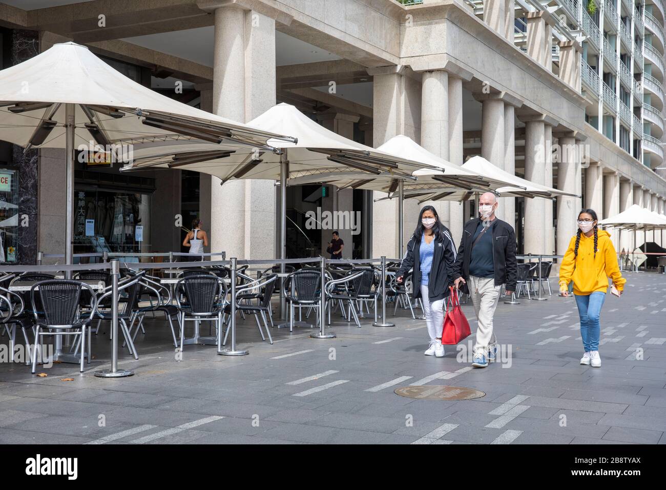 Centro di Sydney, Australia. Lunedì 23 Marzo 2020. La famiglia indossa maschere facciali camminare oltre un ristorante chiuso al Circular Quay. Credit Martin Berry/Alamy Live News Foto Stock